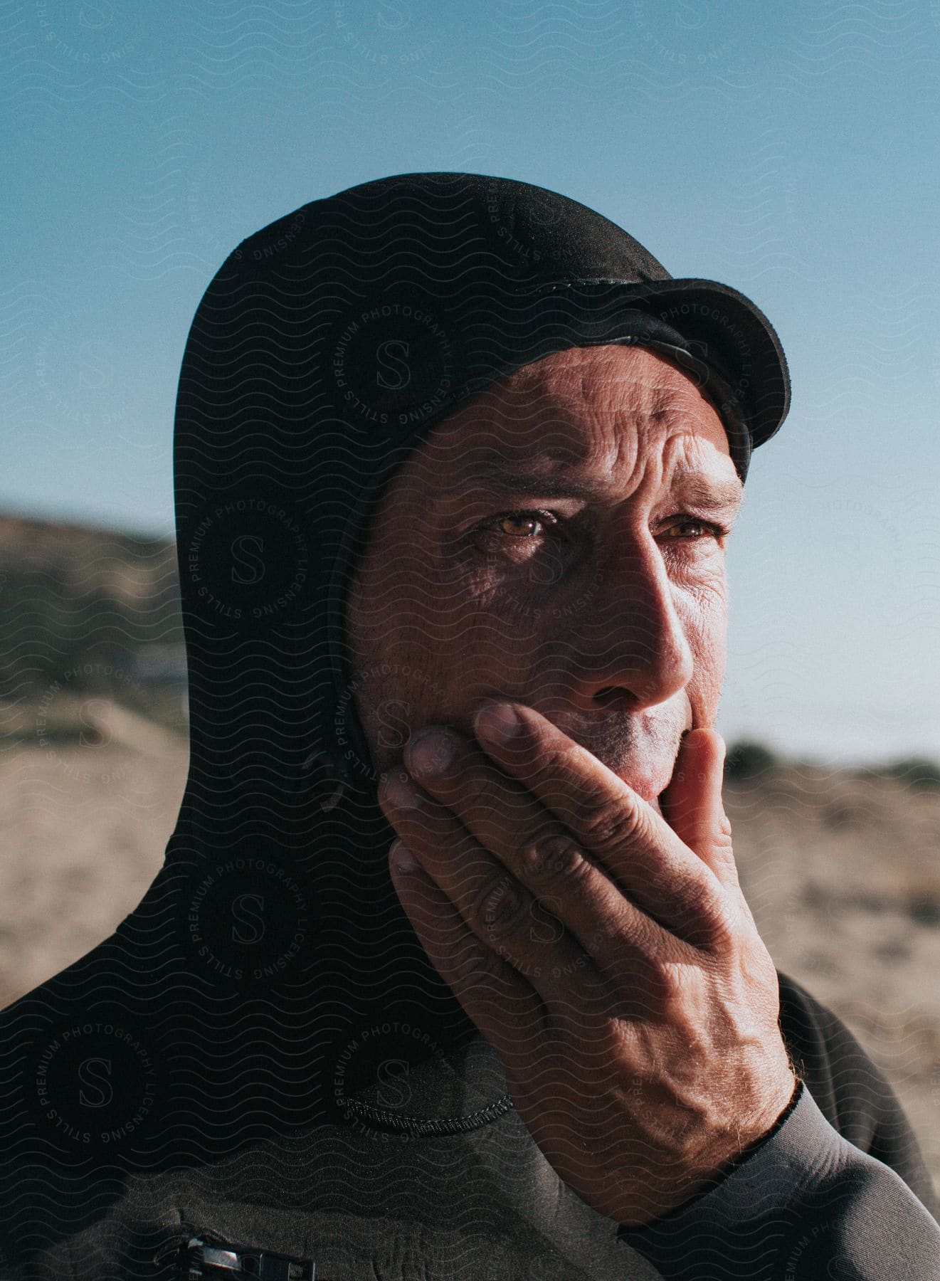 Man in wetsuit touching his chin