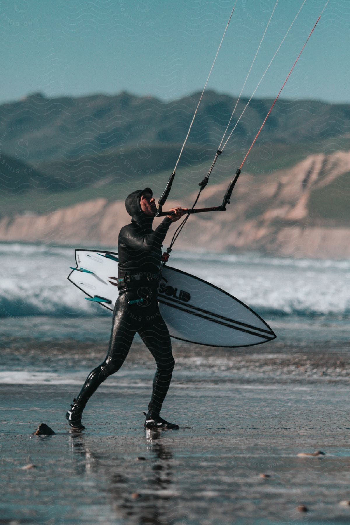 Man in wetsuit with a surfboard on a beach