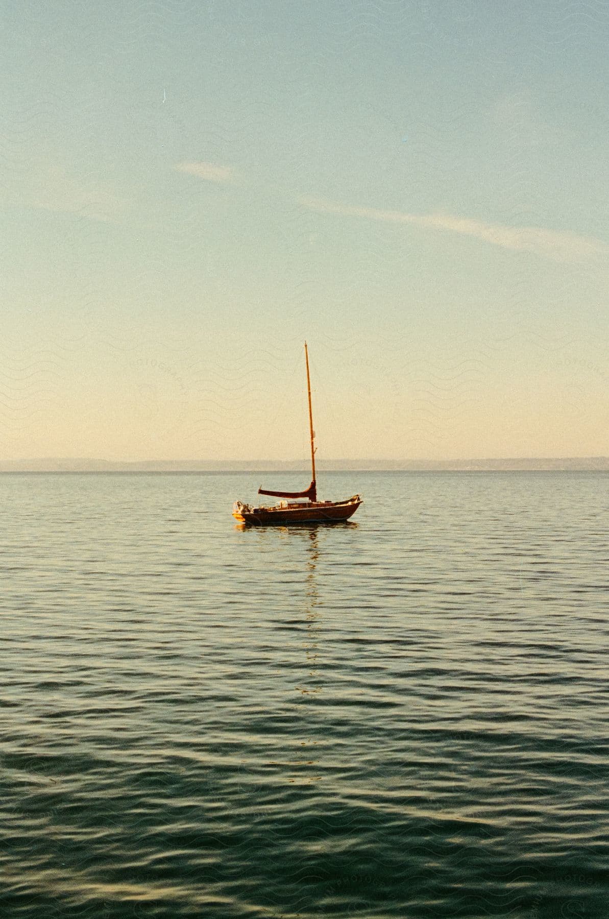 Sailboat floats on ocean water under blue sky