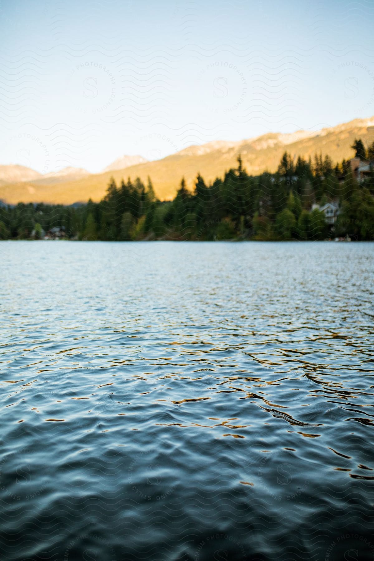 A lake surrounded by mountains and houses in the distance