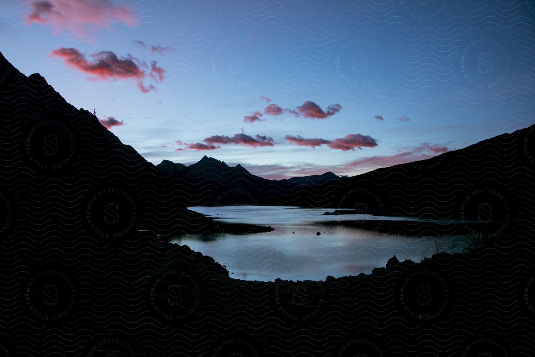 A serene landscape of a mountain range reflected in a calm lake at dusk