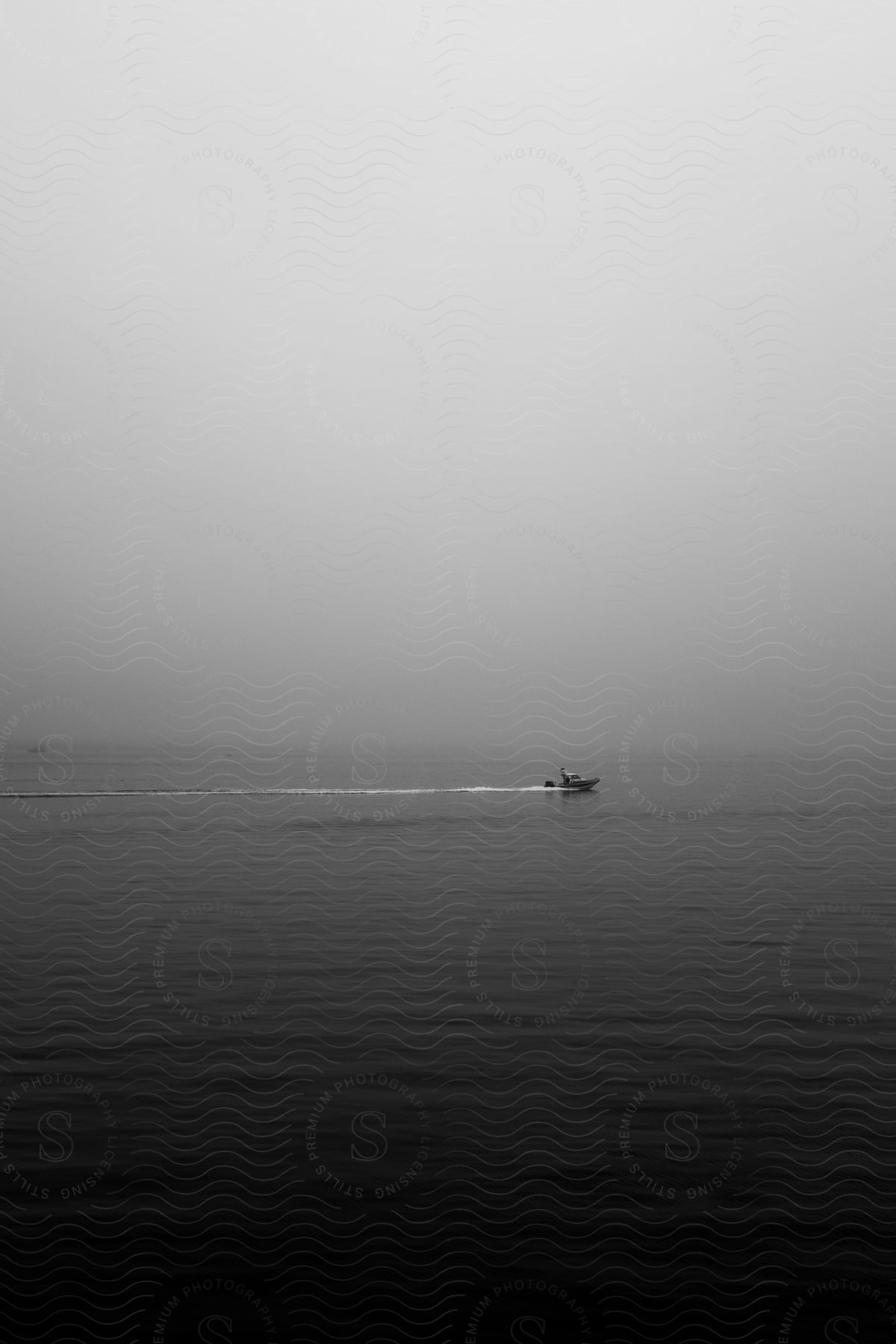 Black and white shot of a boat moving over the calm surface of the ocean