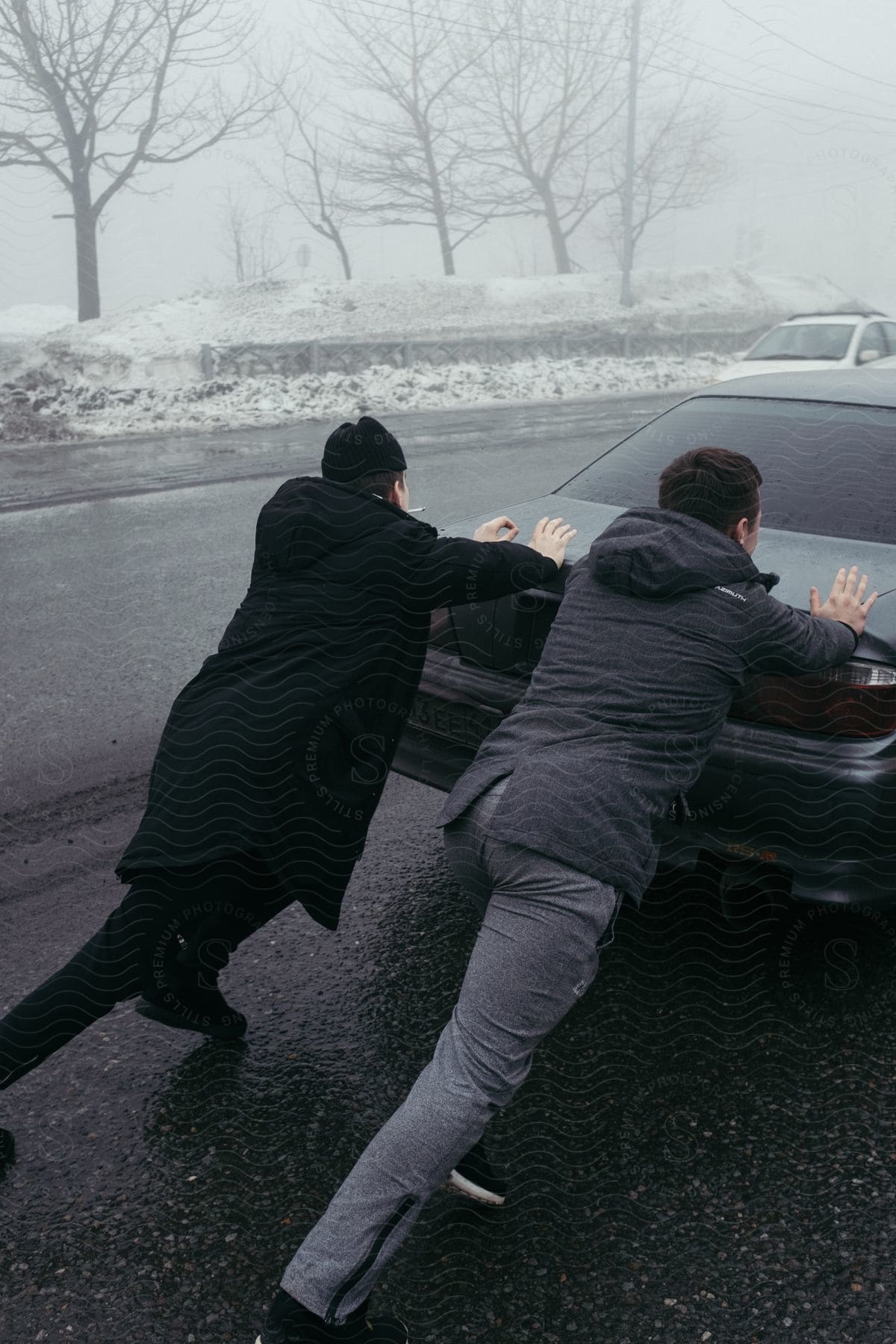 Two men pushing a car on an icy road