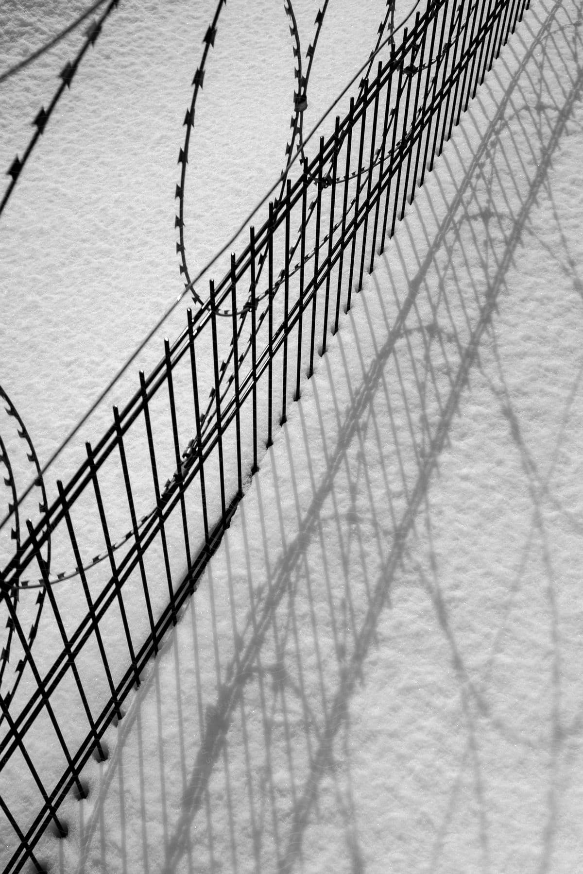A snowcovered fence with razor wire on top