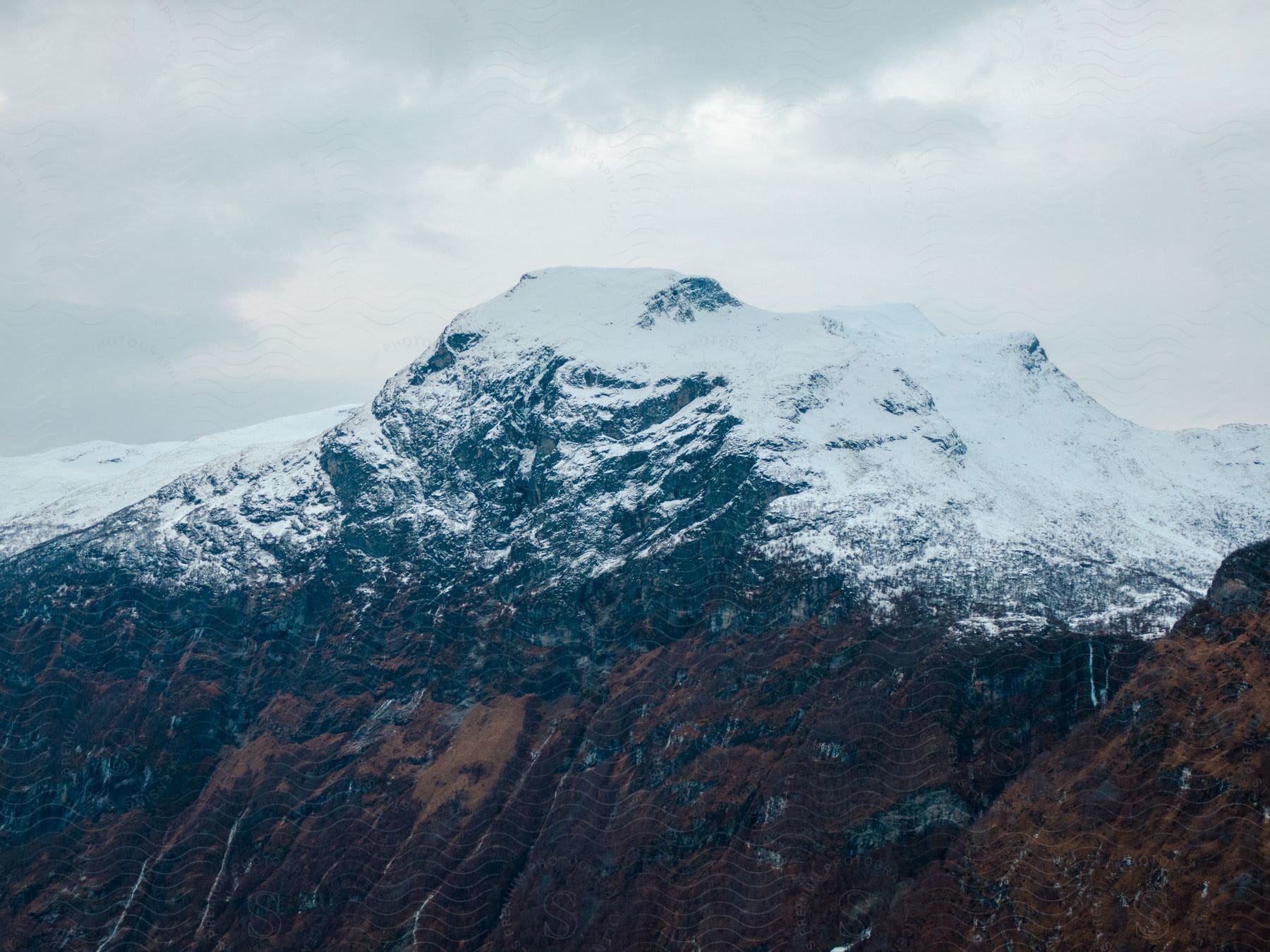 A snowcovered mountain stands tall under a gray sky in norway