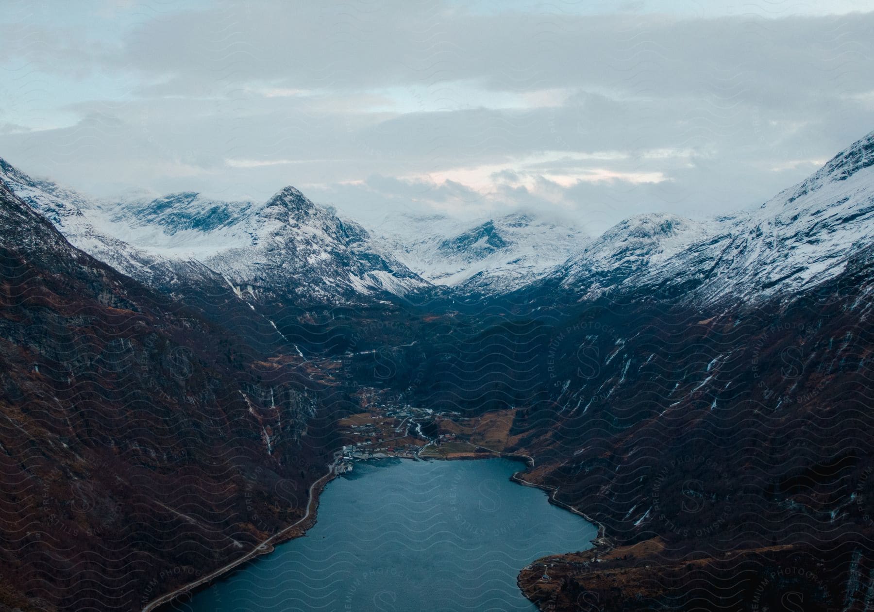 Aerial view of a snowy mountain landscape with a lake and watercourse