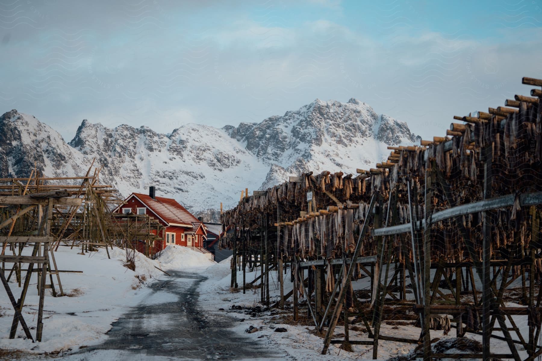 Wooden structures built outside a town close to the snow covered mountains at morning in norway