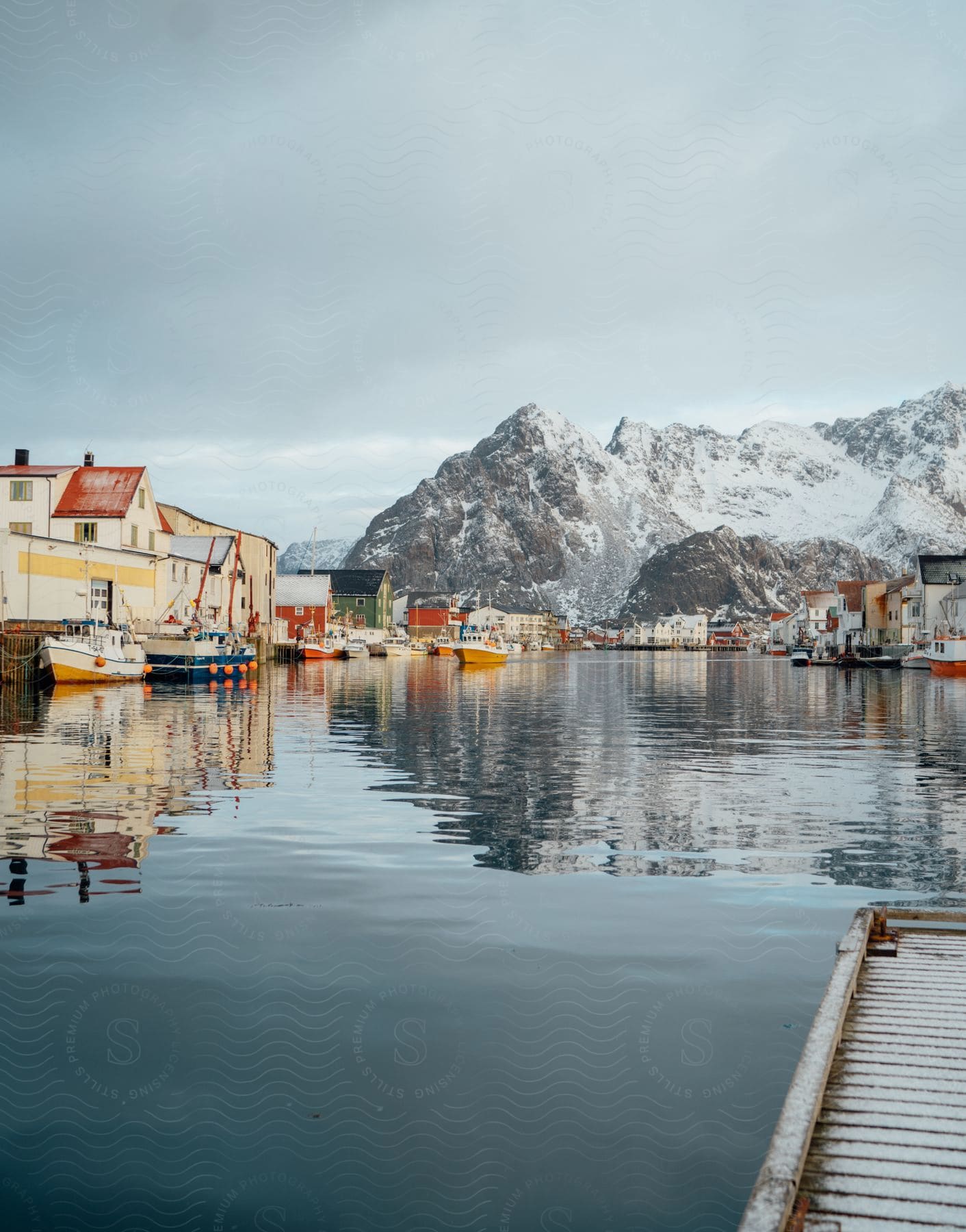 Boats moored to houses in a coastal town near snowcovered mountains in norway