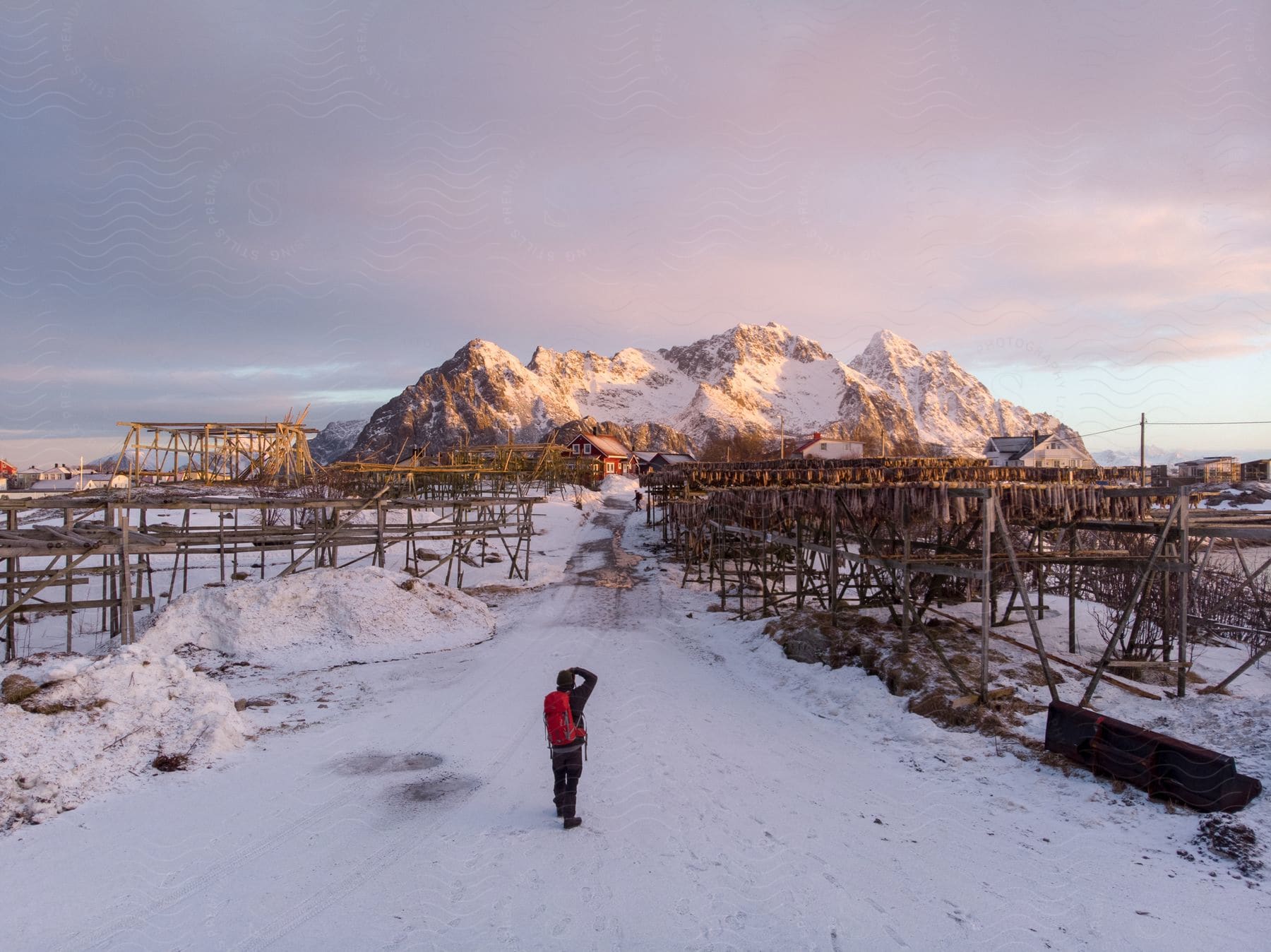 A photographer captures a snowy village with mountains in the background and new wooden construction in the foreground