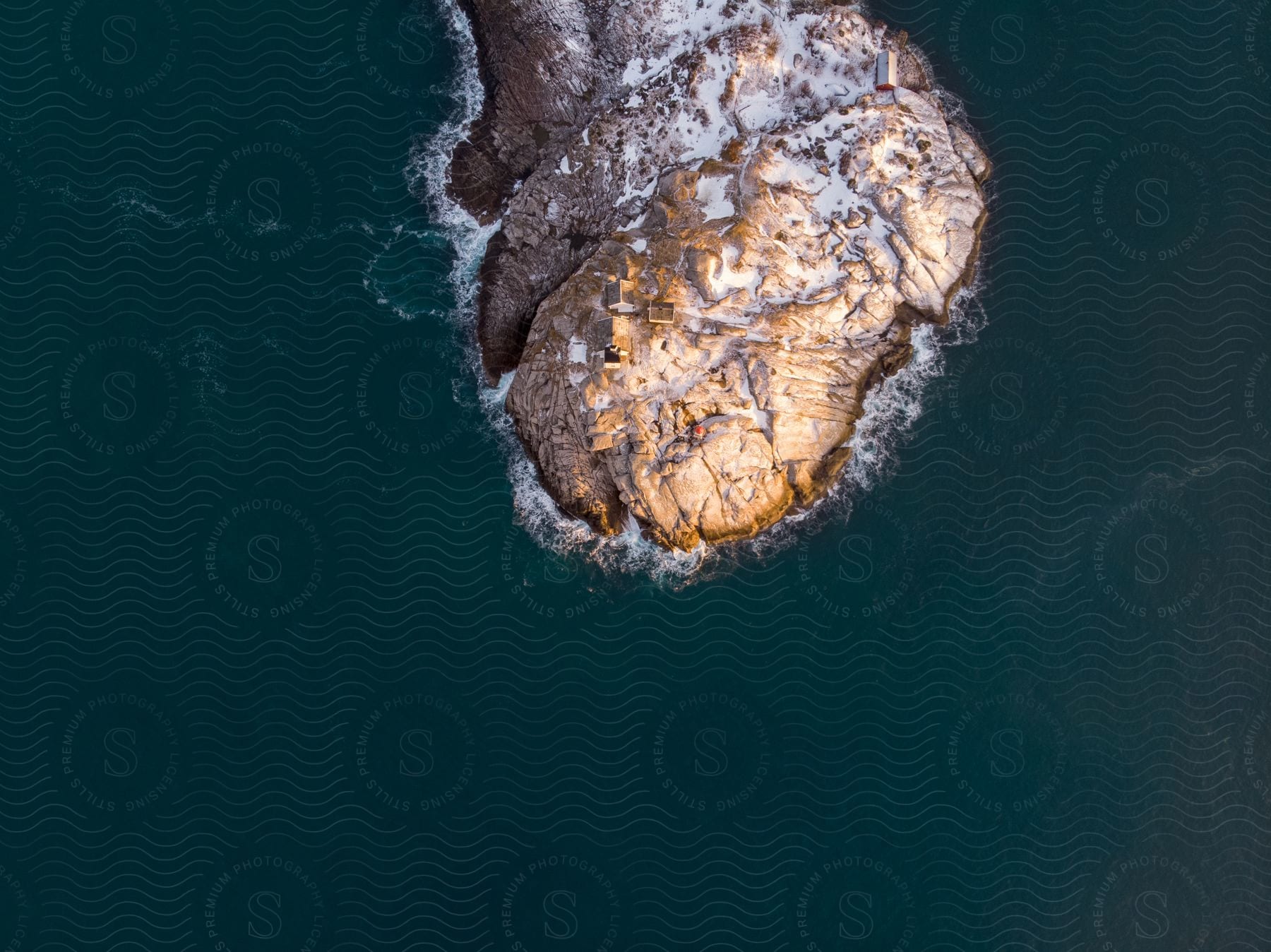 Sunlight shining on the side of an island in the ocean seen from above