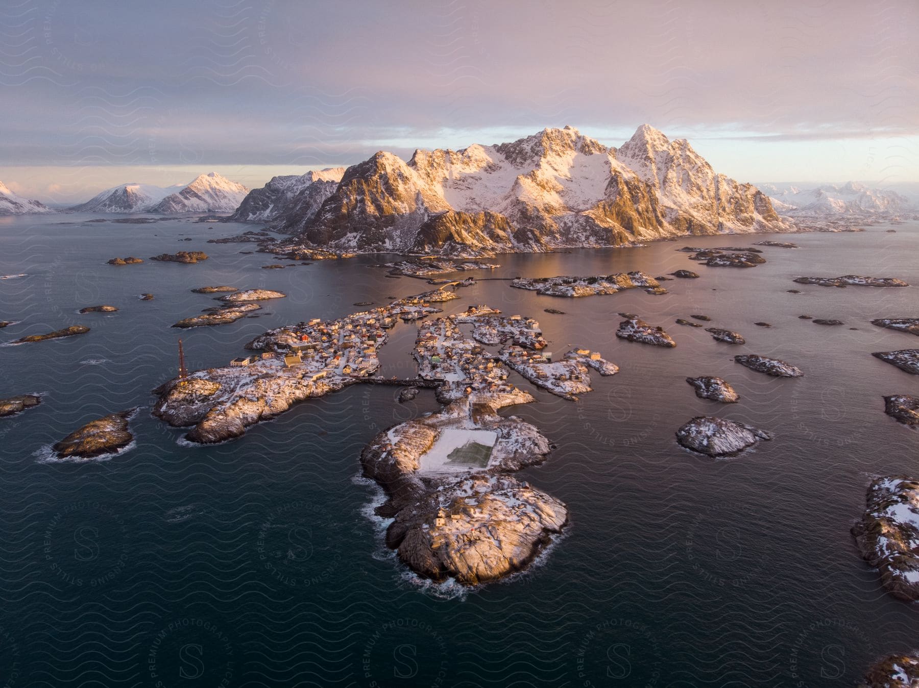 A landscape with scattered rocks by the sea with icecapped mountains on the horizon