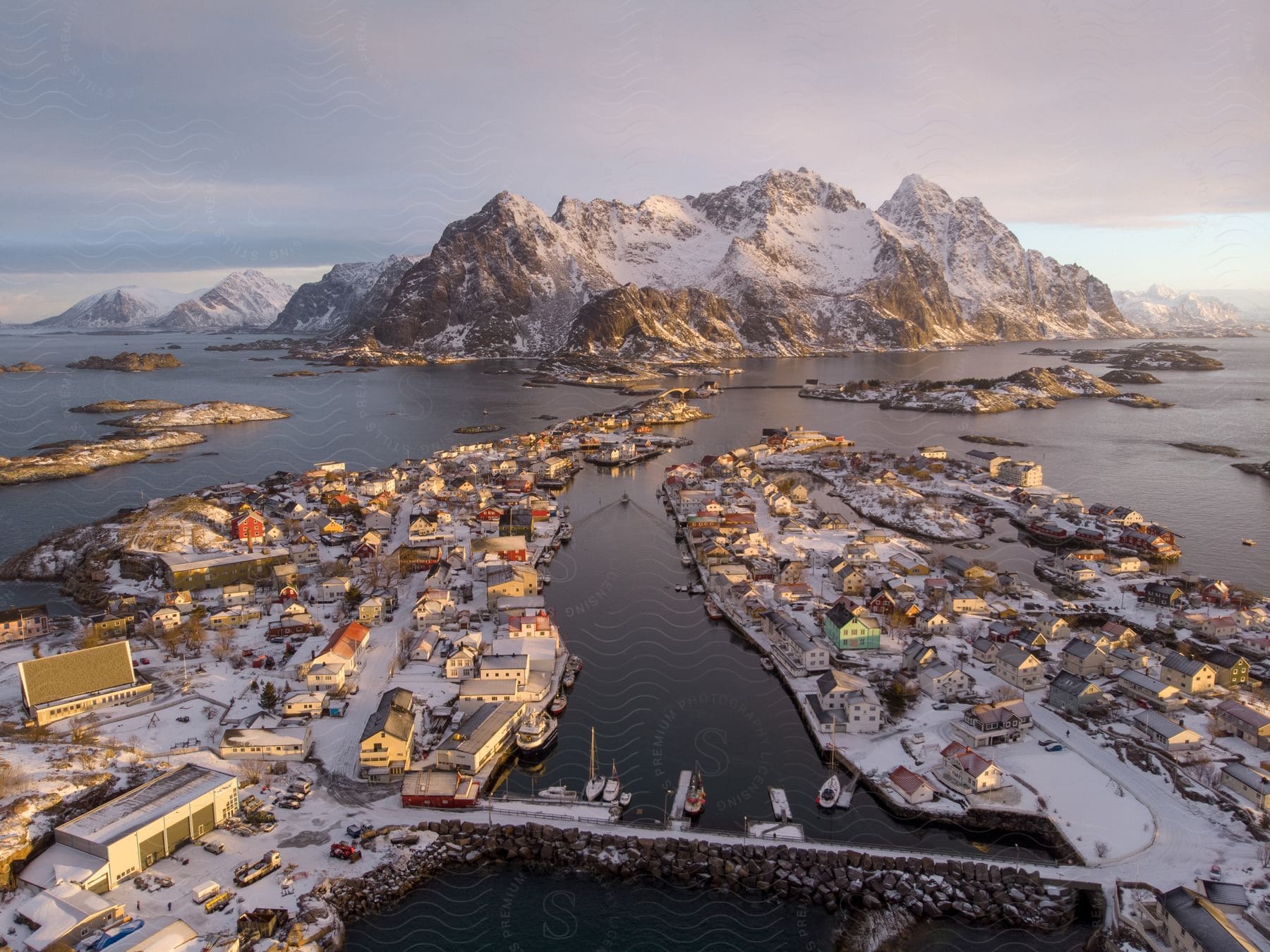 A snowy mountain serves as the backdrop for a city on a river seen at dawn