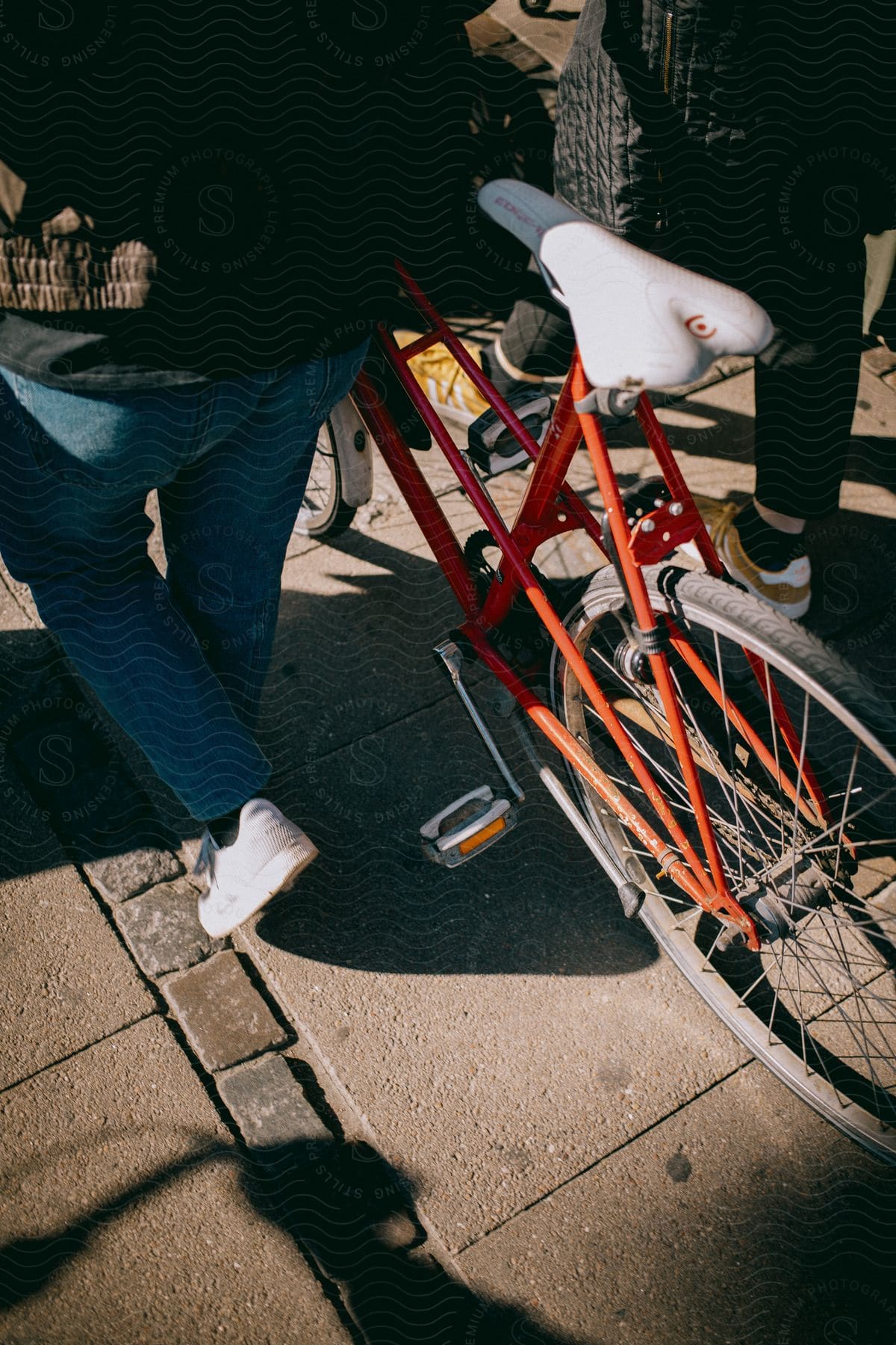 Two people walk their bicycles down the street