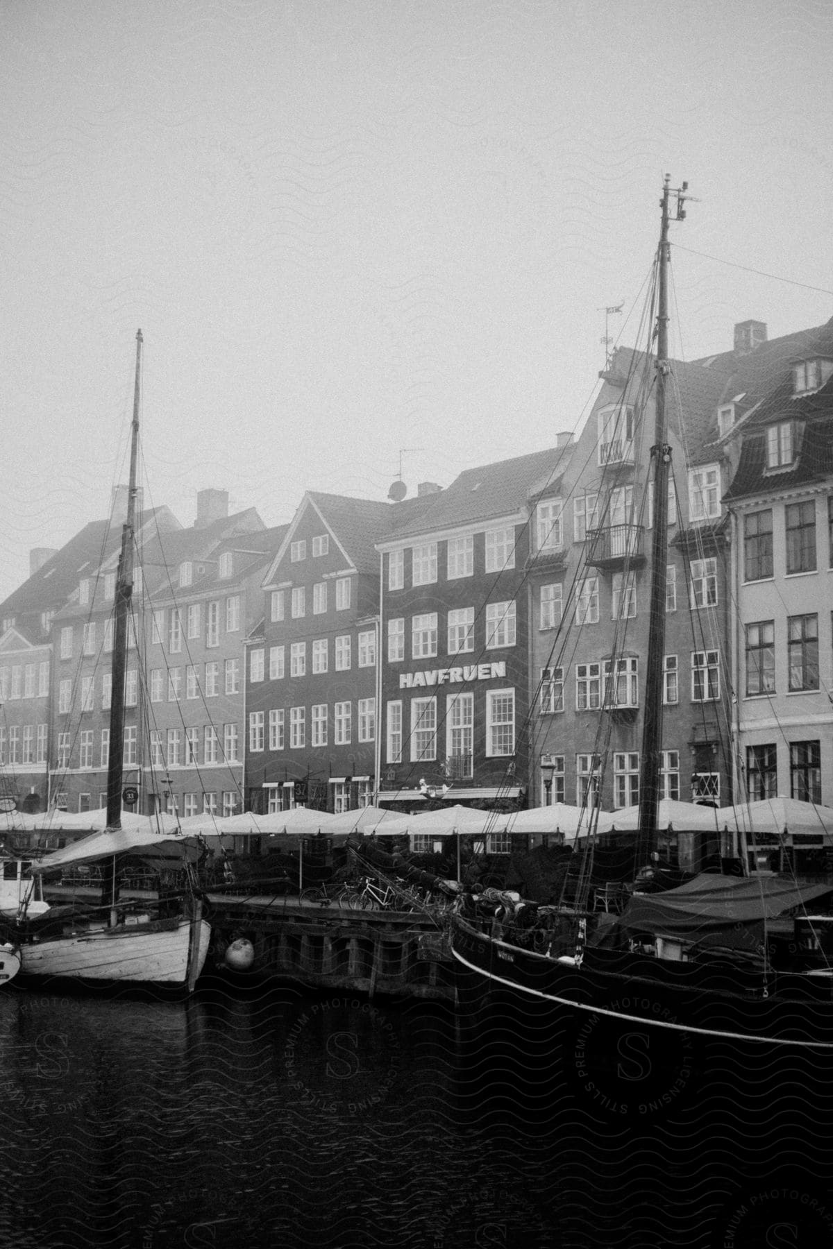 Copenhagen in black and white boats at dock with white shelter covers and tall sidebyside buildings