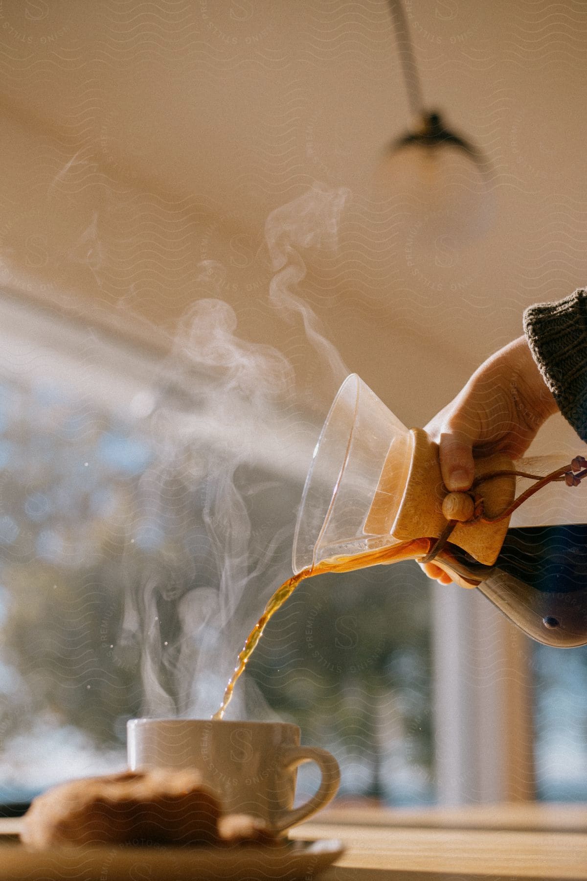 Male hands serving coffee on a cup next to a bagel on a dish