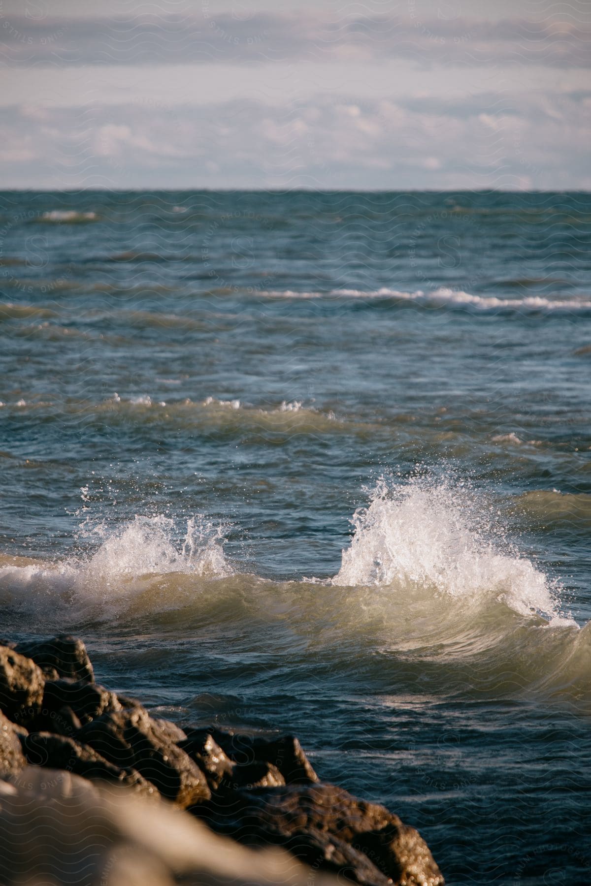 Waves crash on a rocky coast under cloudy skies