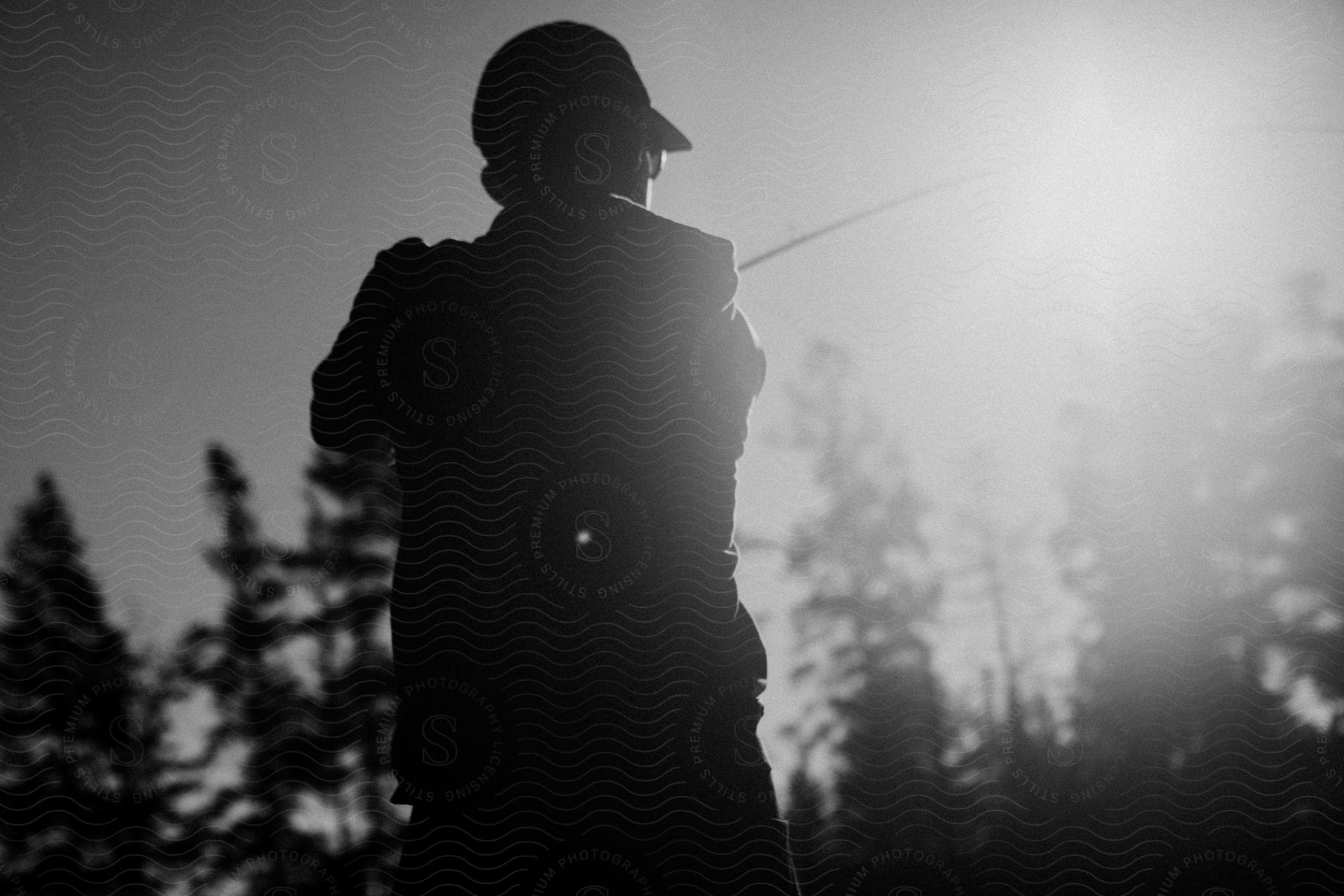 Silhouette of a man fishing on a river in the forest