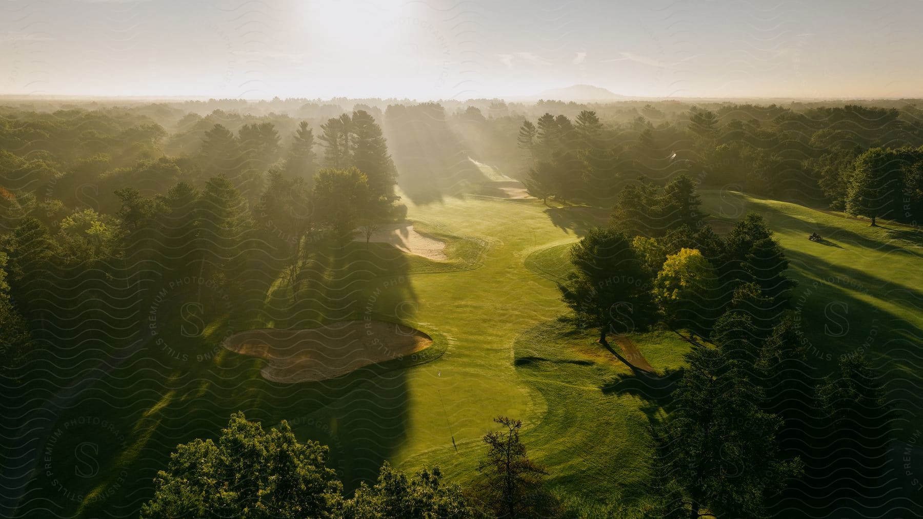 Aerial shot of a lush green golf course in the rising sun