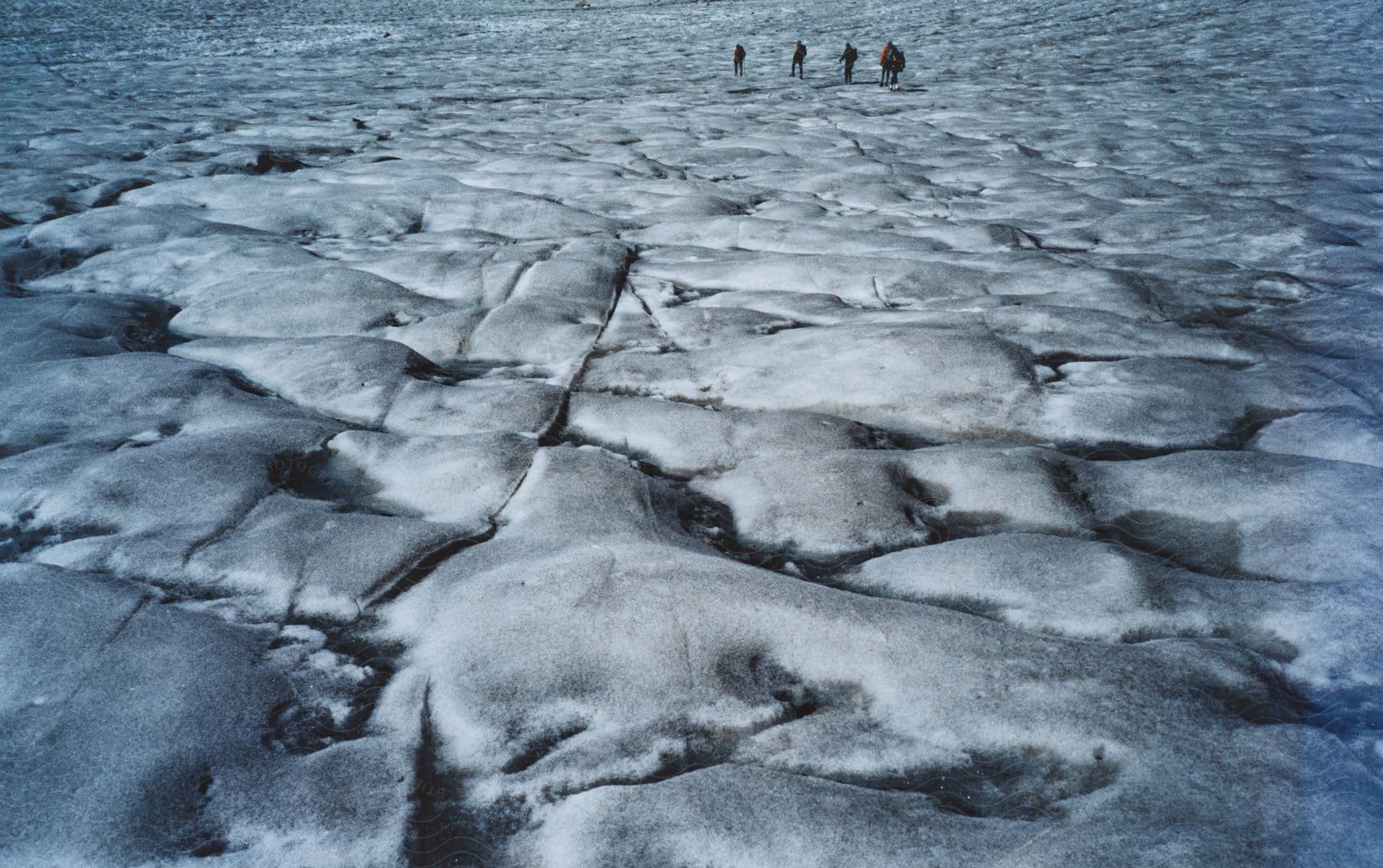 A group of people walking across an ice cap in the swiss alps during a winter hike