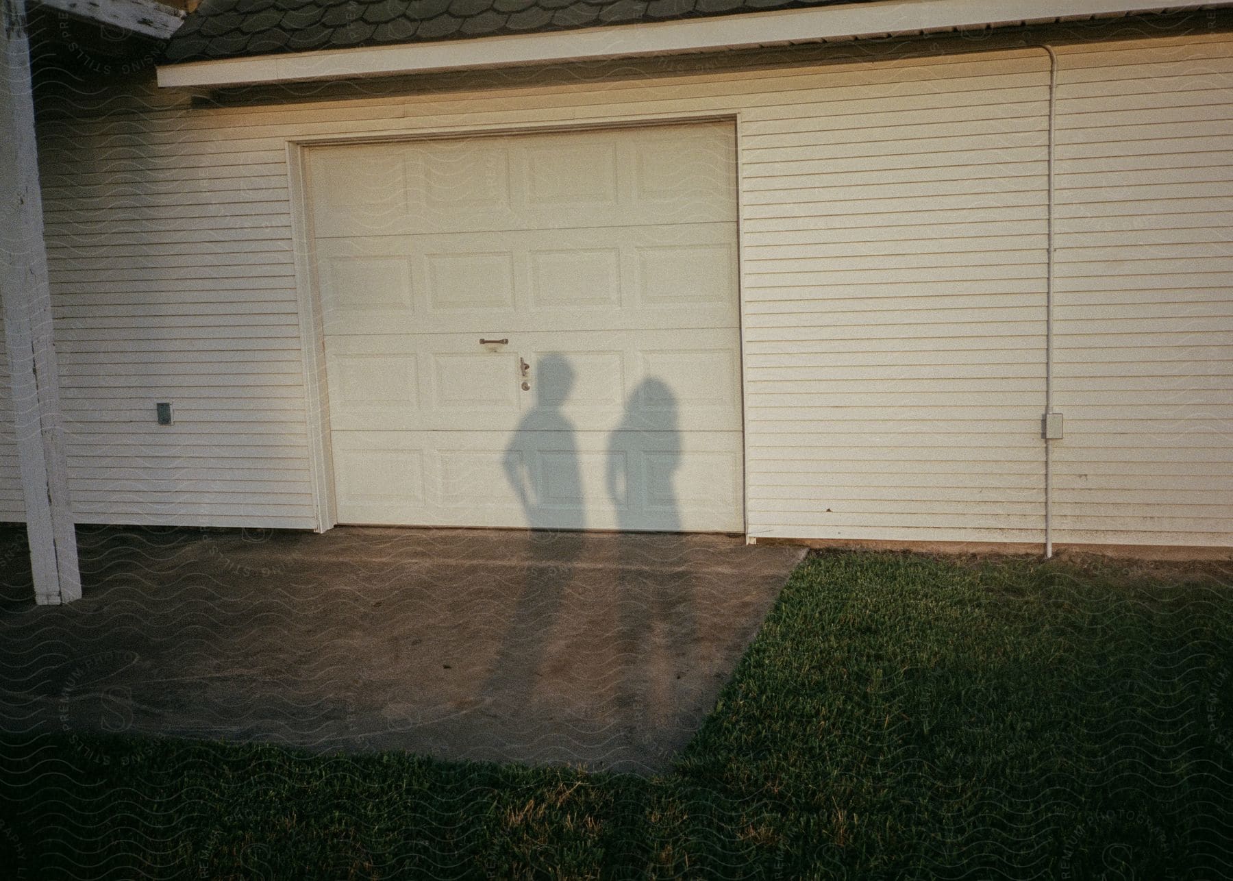 A garage door casts the shadows of a man and a woman