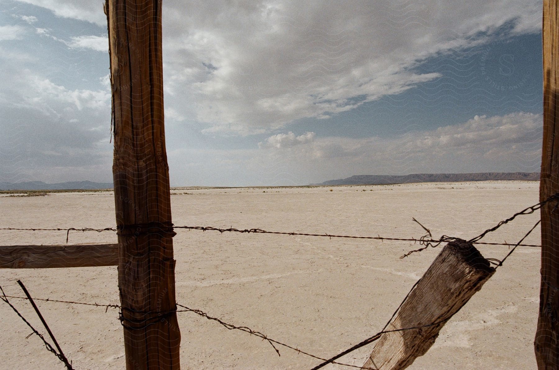 Abandoned wooden fence with barb wire next to the desert