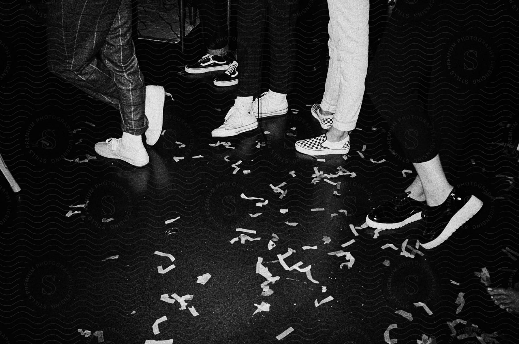 People with sneakers showing their legs in a black and white image taken indoors