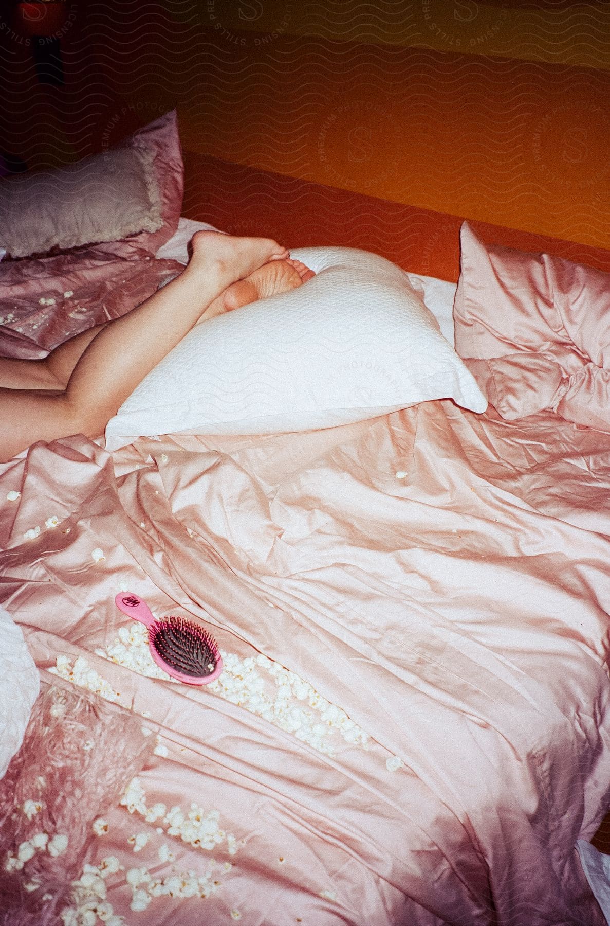 A teenage girls messy bed with her legs resting on a pillow