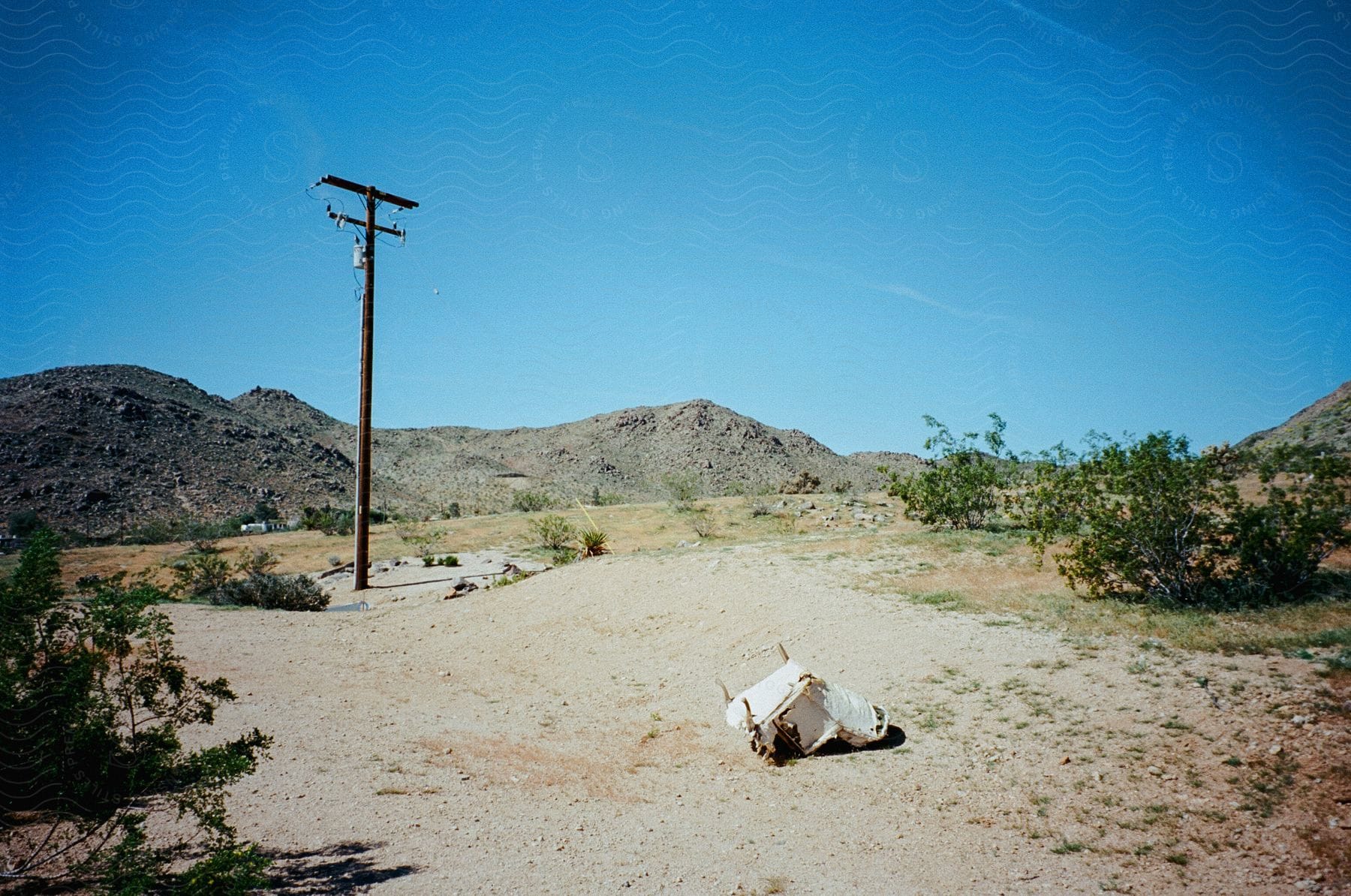 A tattered chair is turned upside down in arid terrain in joshua tree