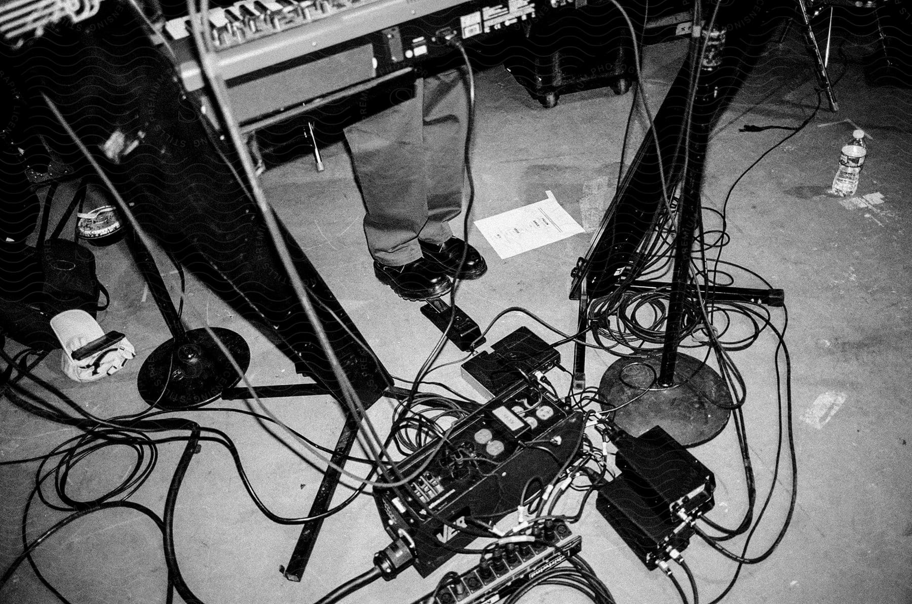 Person standing at keyboard and sound equipment with wires on floor