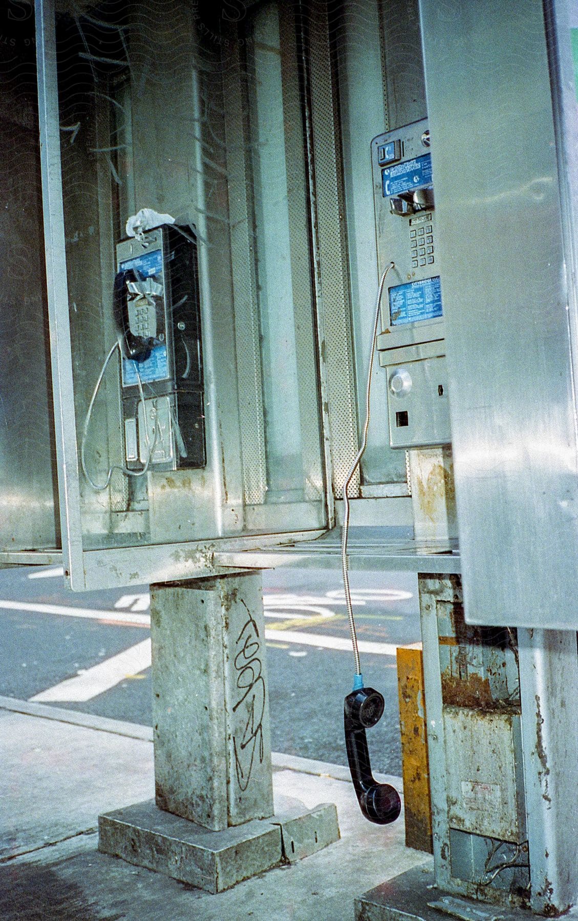 Two pay phones are shown one with its phone hanging