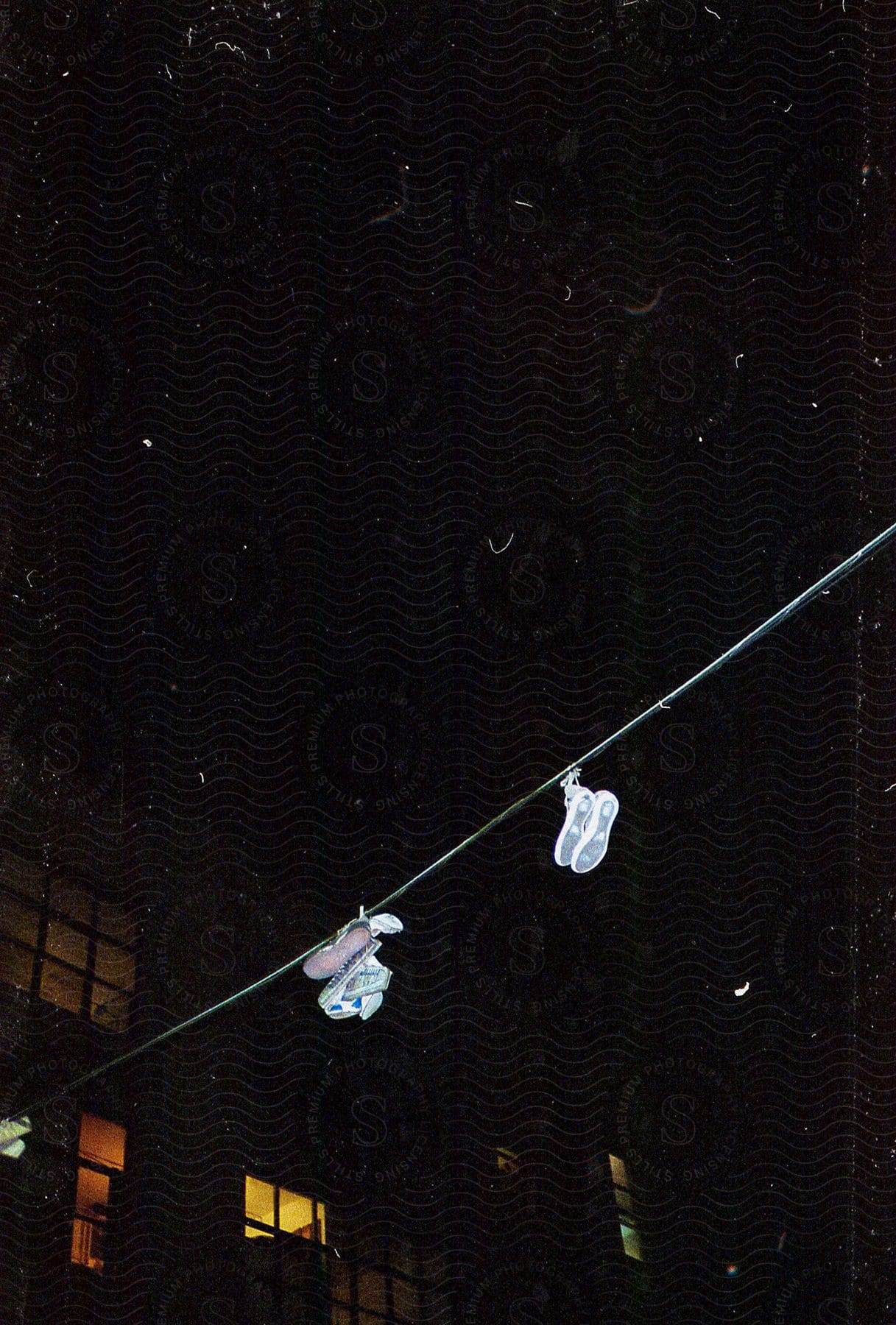 White shoes hanging from telephone wire near sketchy apartment building at night
