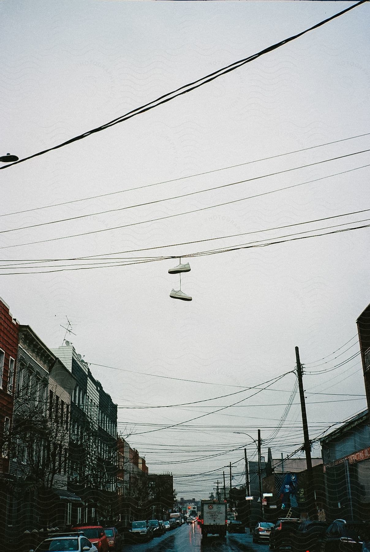 Sneakers hanging on a power line over a city street with cars