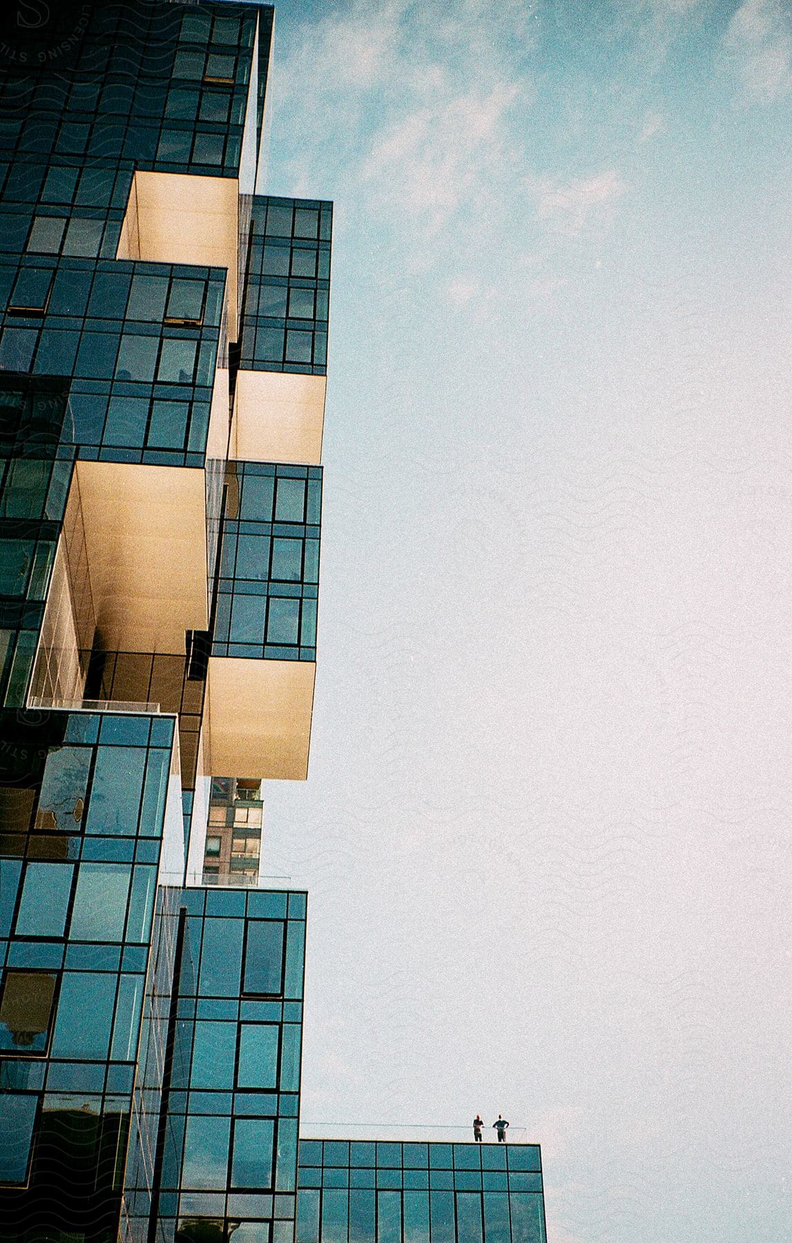 Two people stand on the patio of a modern building with floortoceiling windows in nyc