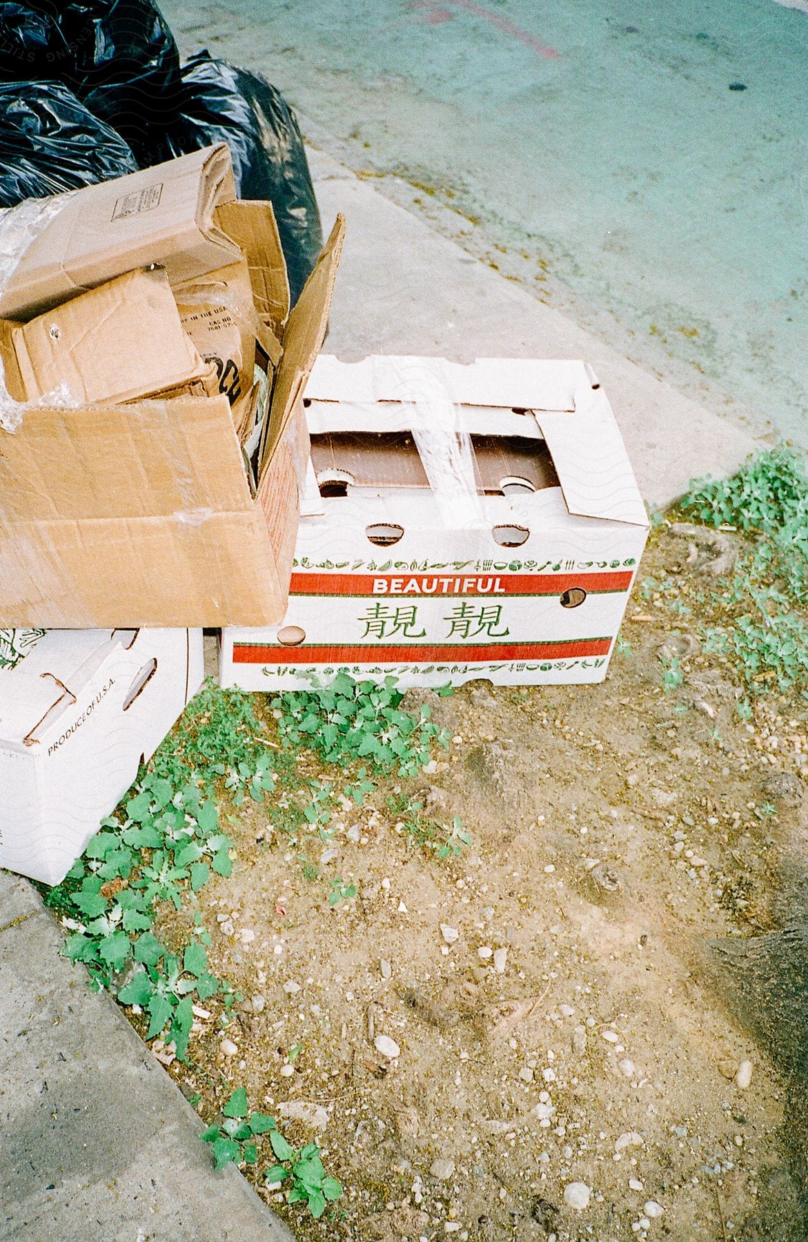 Trash bags and empty boxes sitting on the side of the road