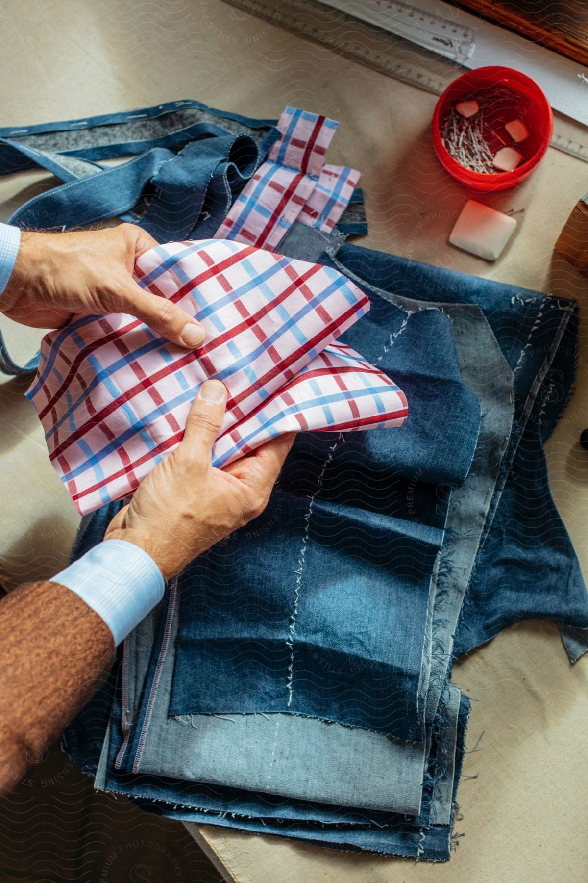 Clothing designer holding red white and blue fabric over strips of denim