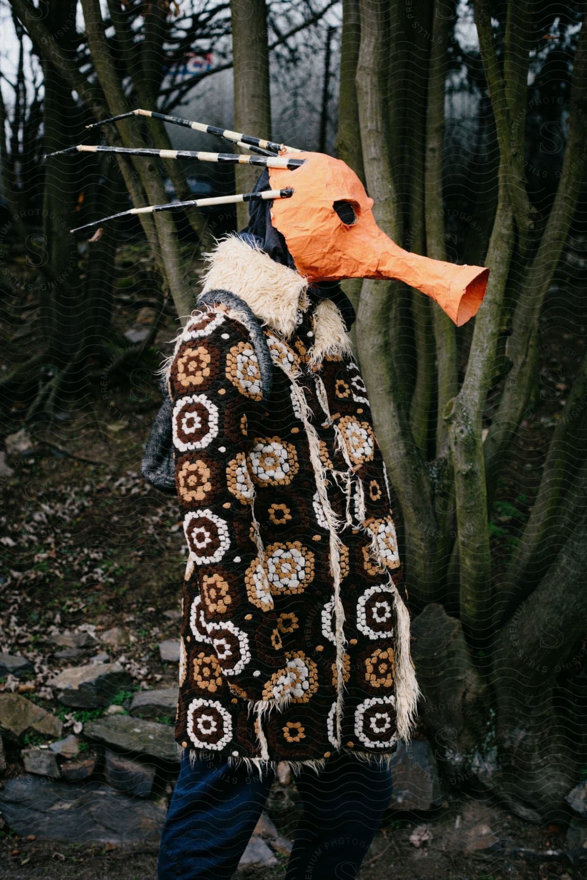 Person posing outdoors in traditional clothes and a creepy mask