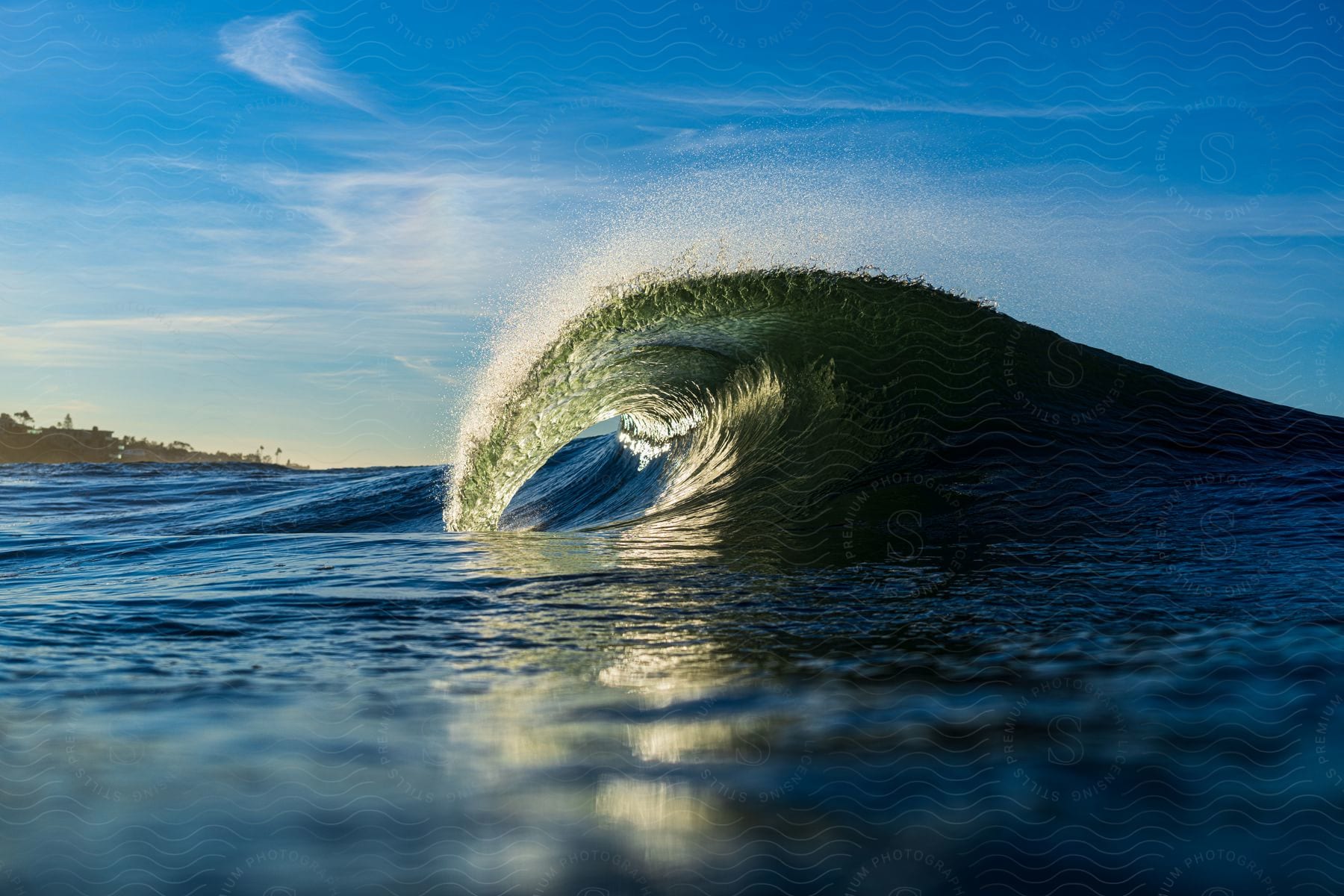 Mist rises from a splashing wave as it curls rolling into shore