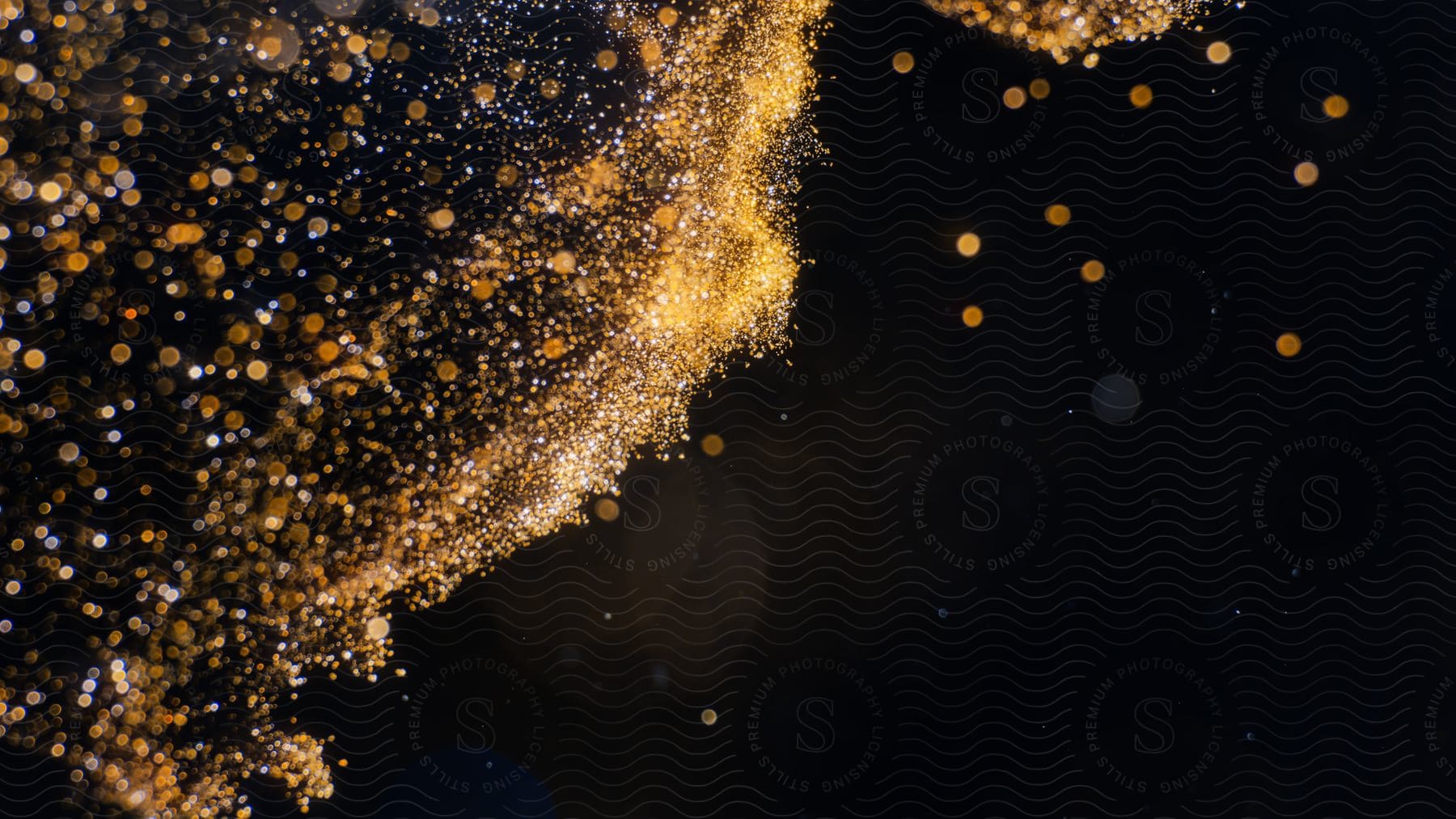 Abstract glitter of golden powder on black background