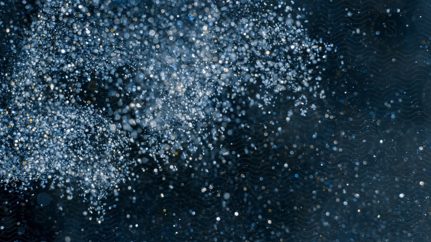 Scattered abstract powder creates mesmerizing textures and patterns on a black background