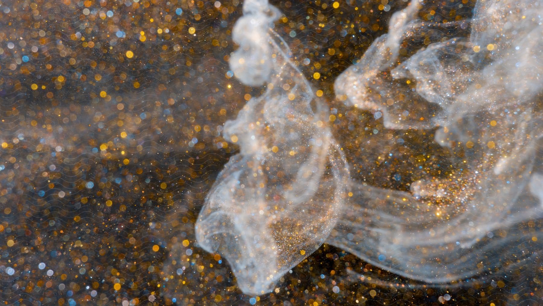 Smoke curls across a black liquid with gold glitter