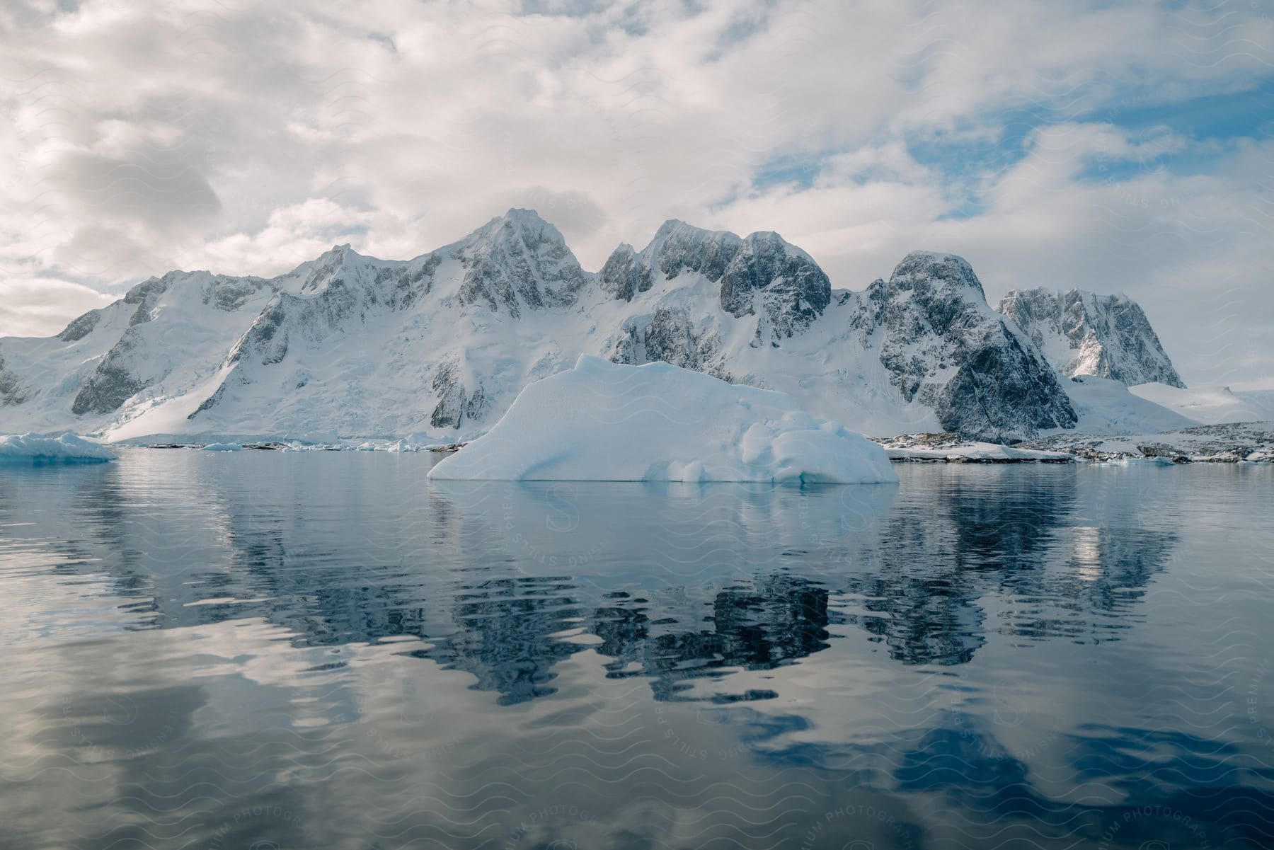 A snowcovered mountain surrounded by water during the day