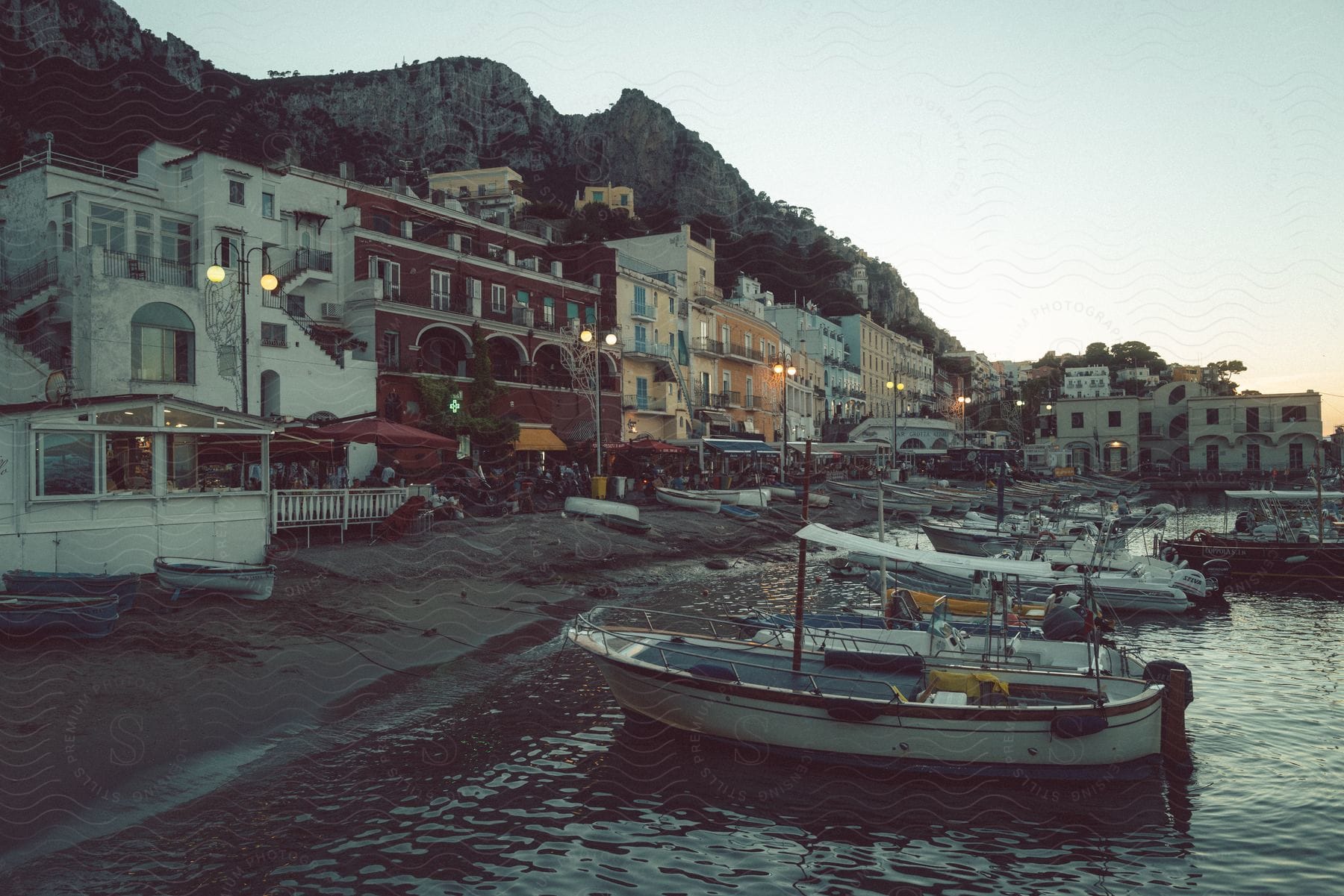 Crowded street near the shoreline with boats docked next to it