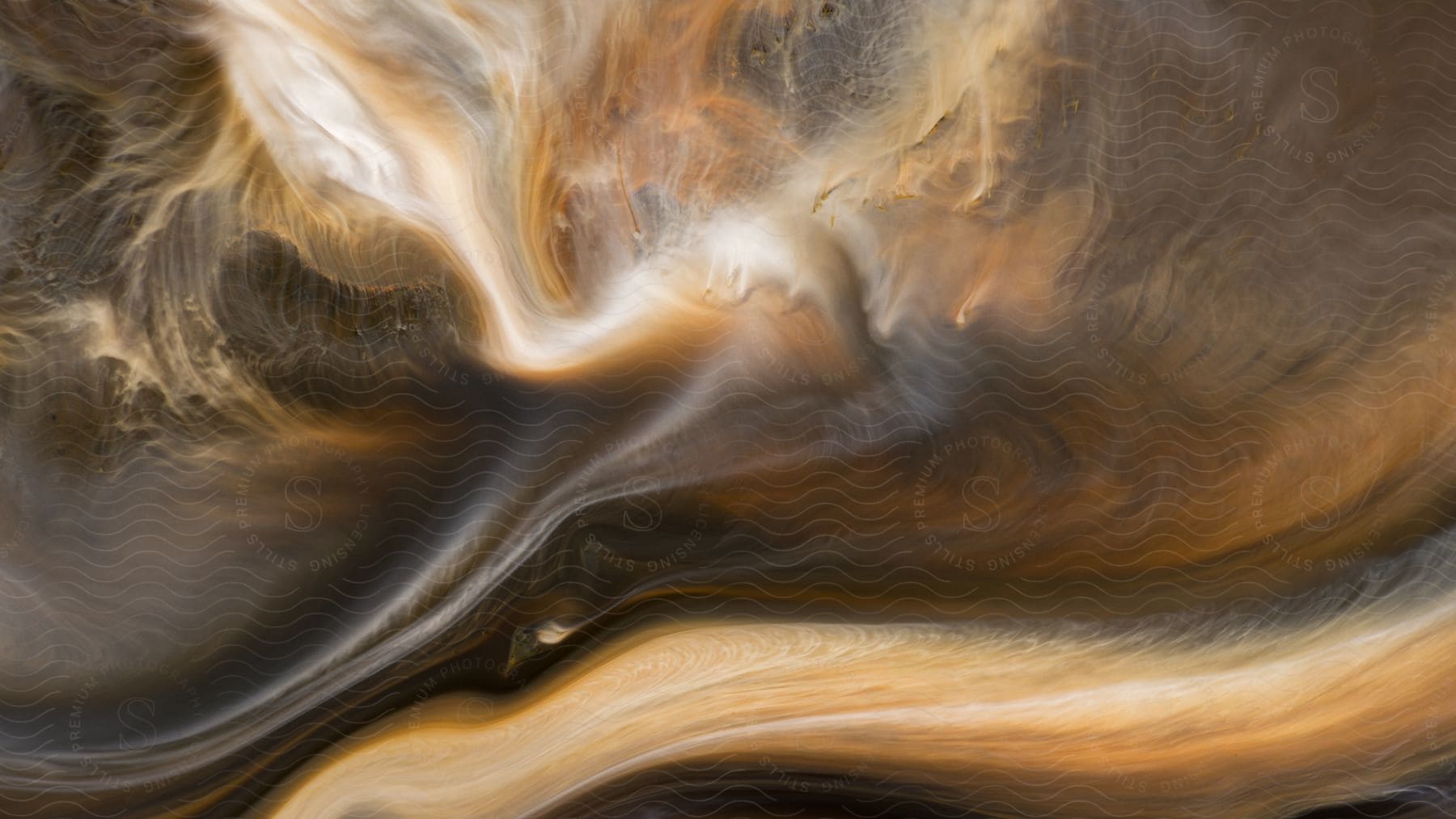 Dark brown and white liquids swirling together