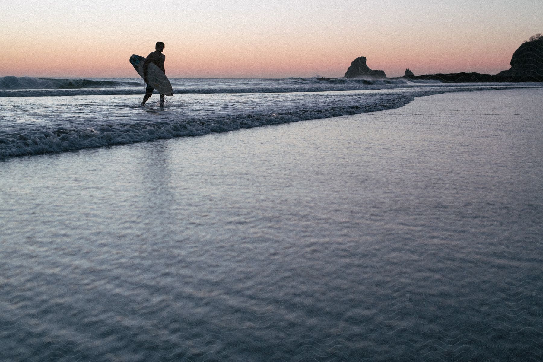 A man walking on the beach with a surfboard