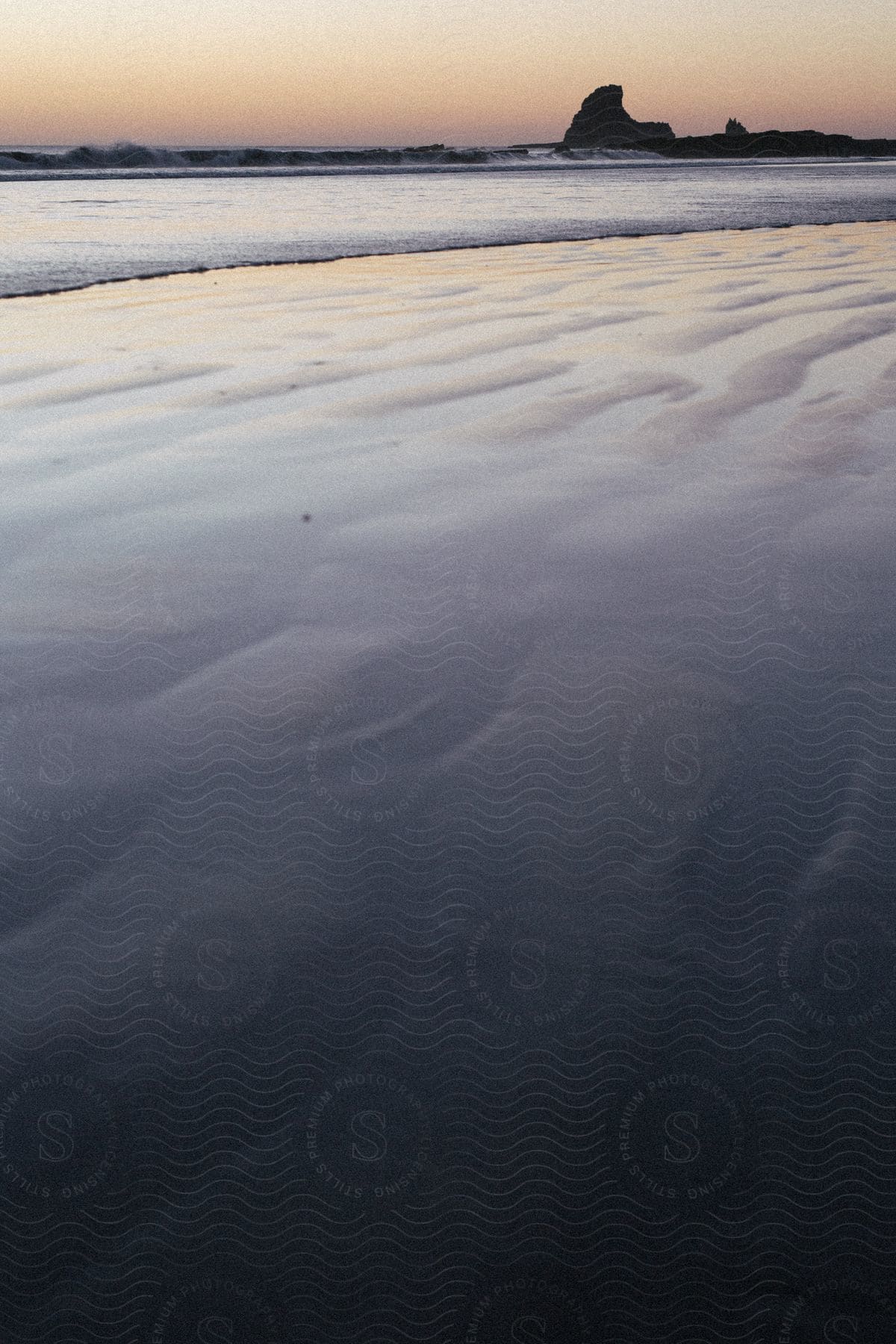 A coastal scene at dusk with the ocean and beach