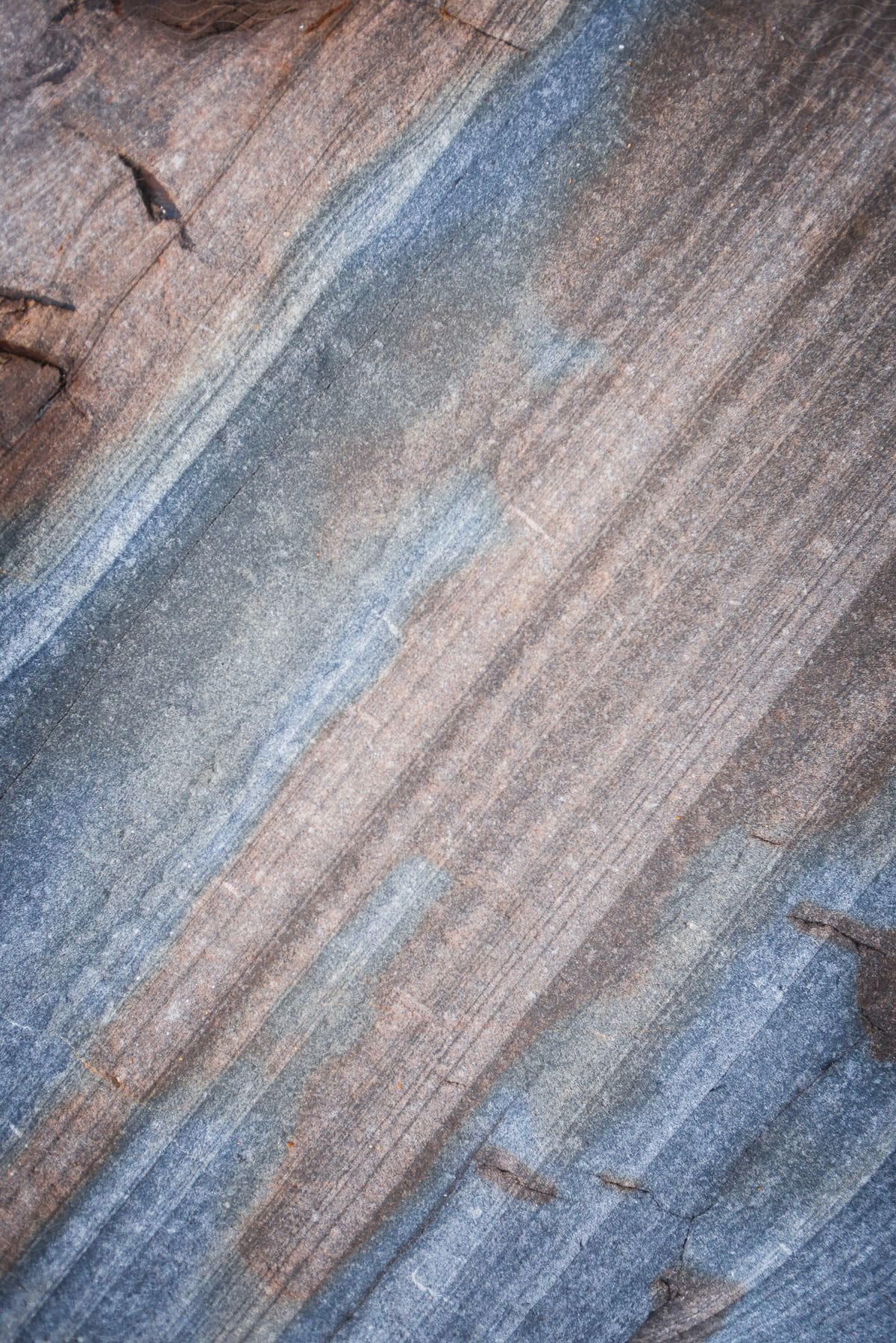 A brown and grey rock with thin diagonal lines