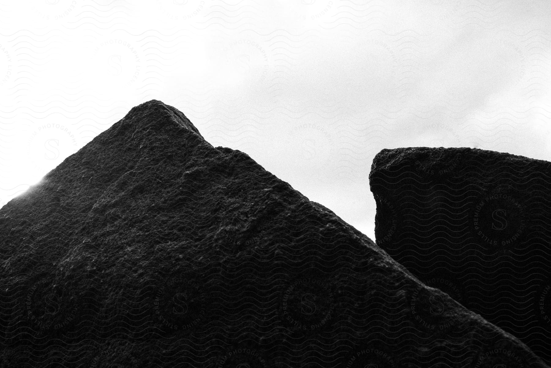 A photograph of a natural landscape featuring a mountain range and cloudy sky in shades of grey