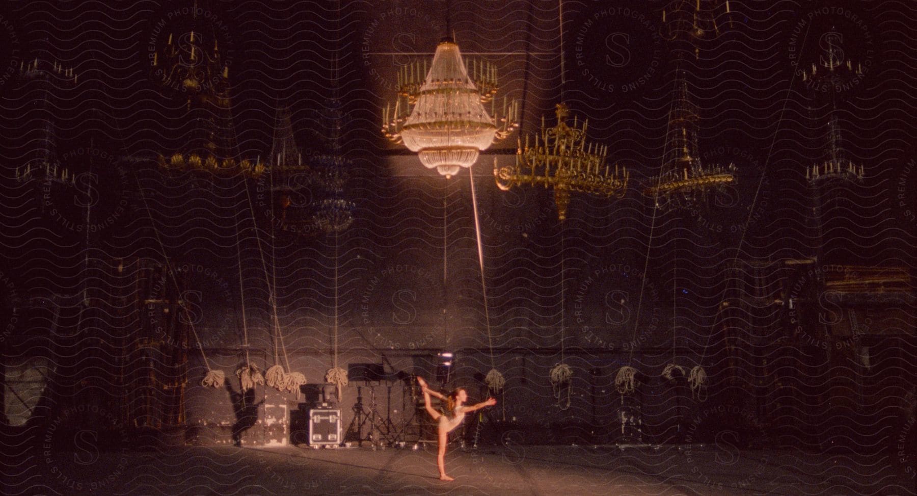 A ballet dancer rehearses a move on an empty stage