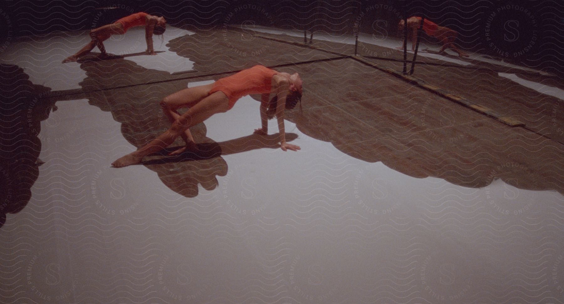 A ballet dancer poses while leaning back on the ground in a mirrored room