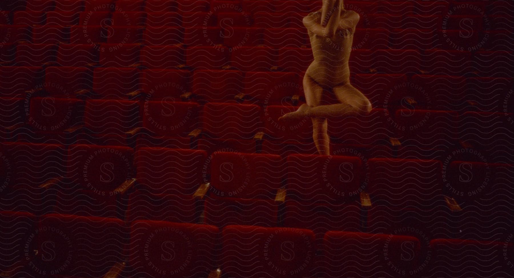 A woman stands alone in a hall filled with red chairs